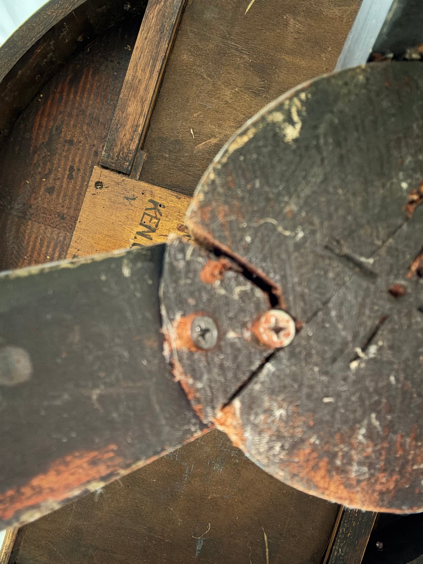 Rust-covered metal object with a visible brand name on a wooden surface