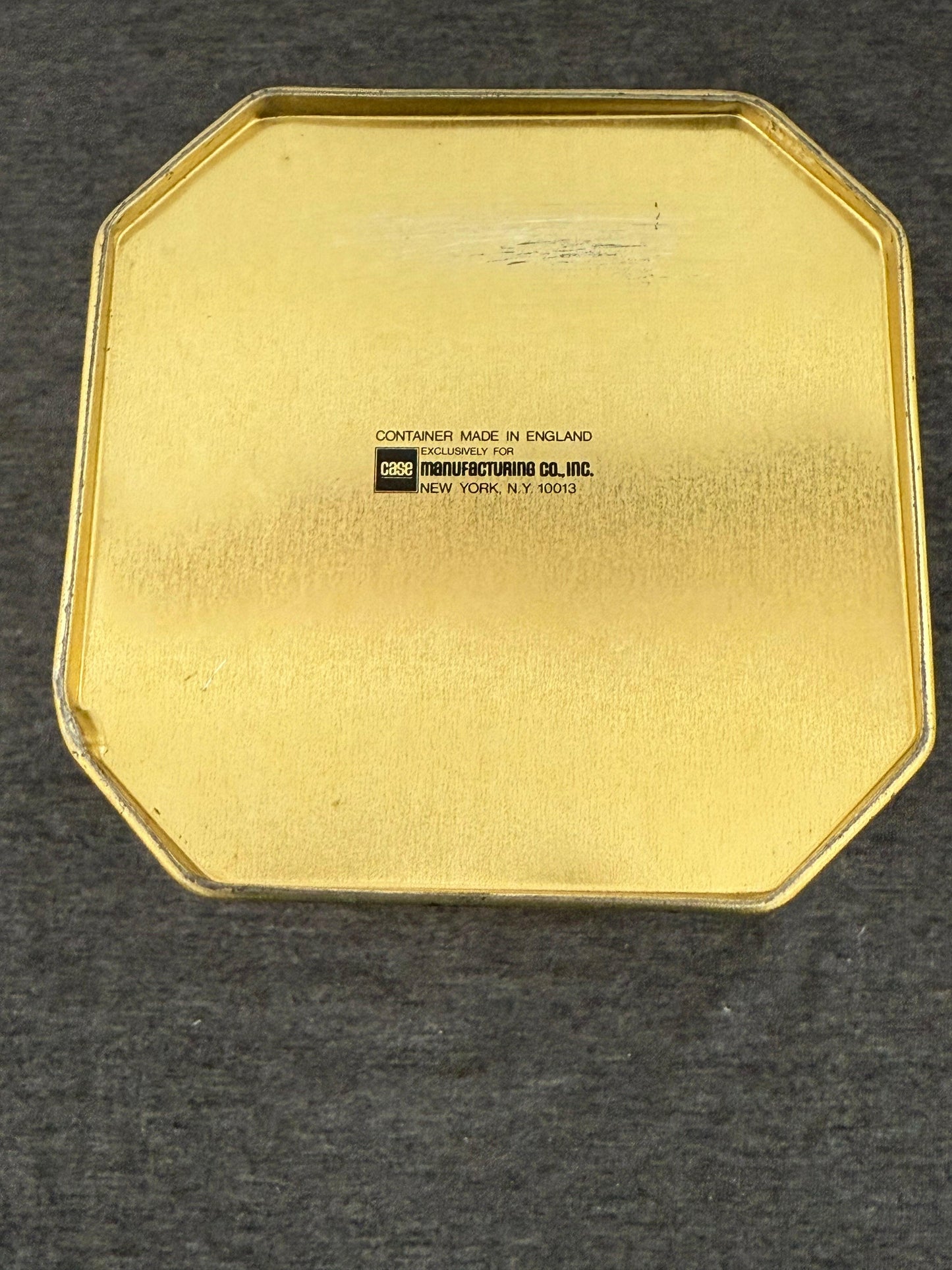Gold octagonal container lid with a black label on a dark background