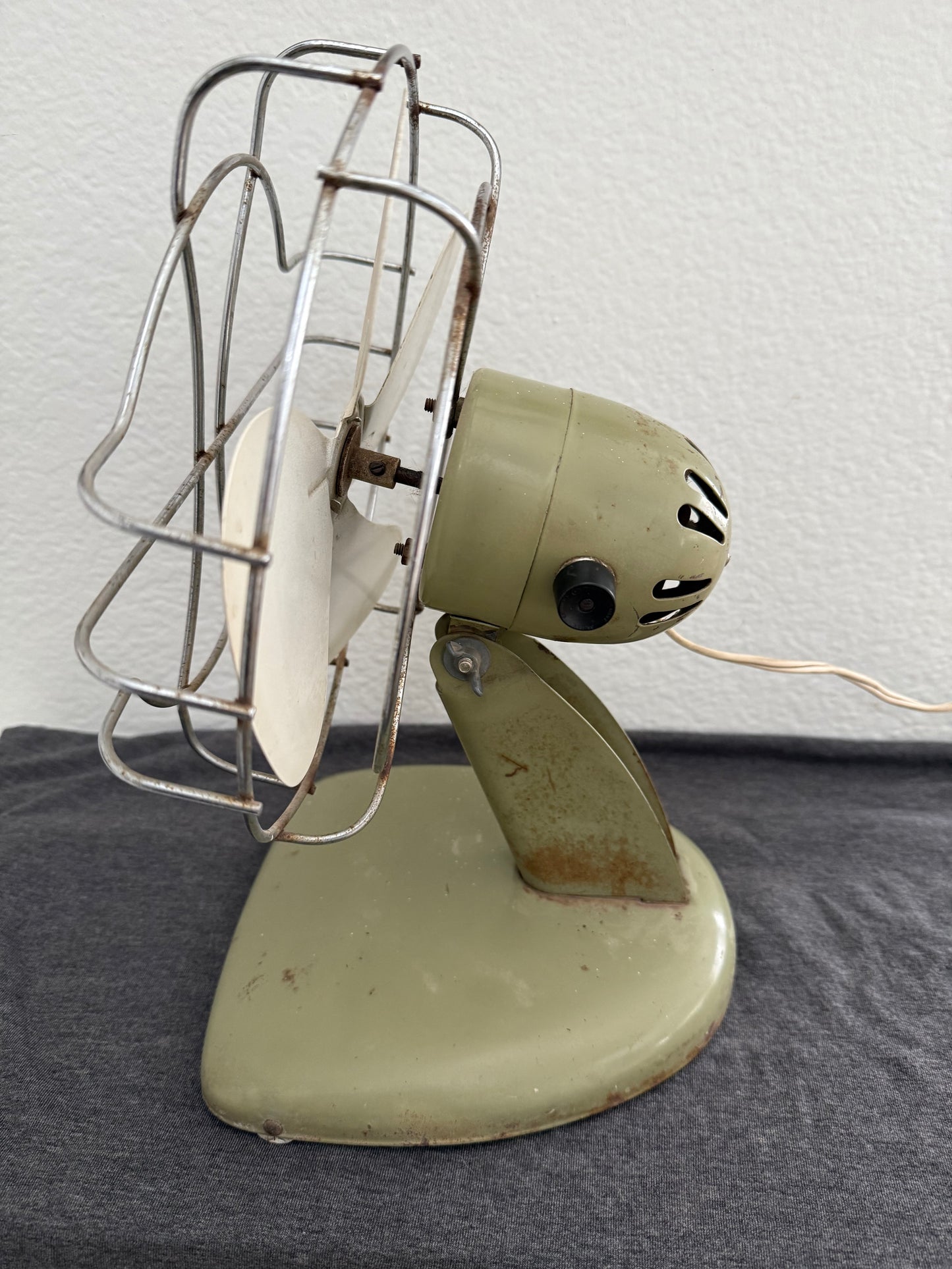 Vintage-style desk fan with white blades and metal frame against a neutral background