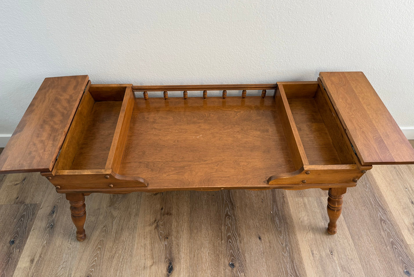 Wooden coffee table with two doors open on a wooden floor.