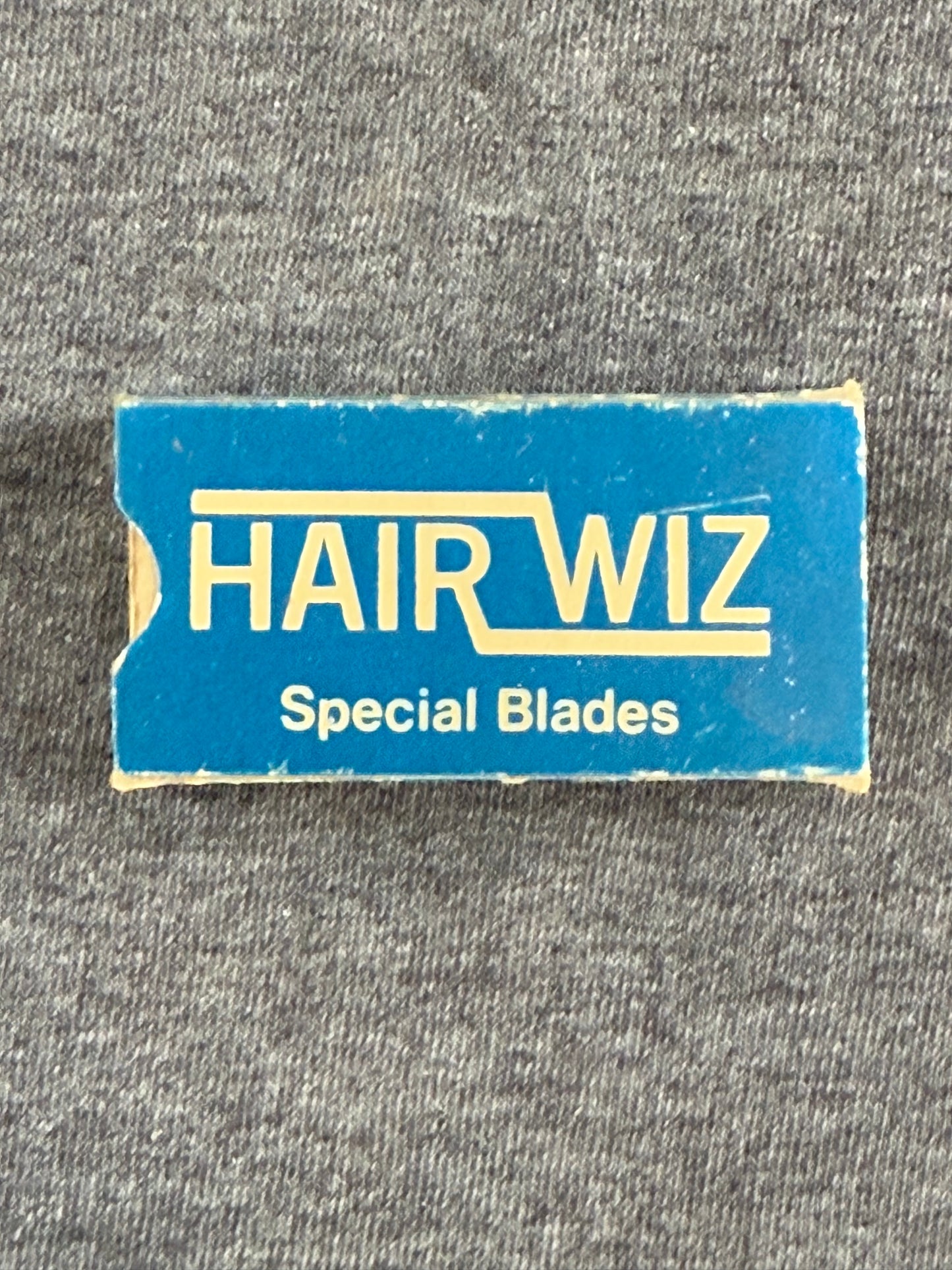 Blue and yellow box for HAIRWIZ Special Blades on a gray fabric background