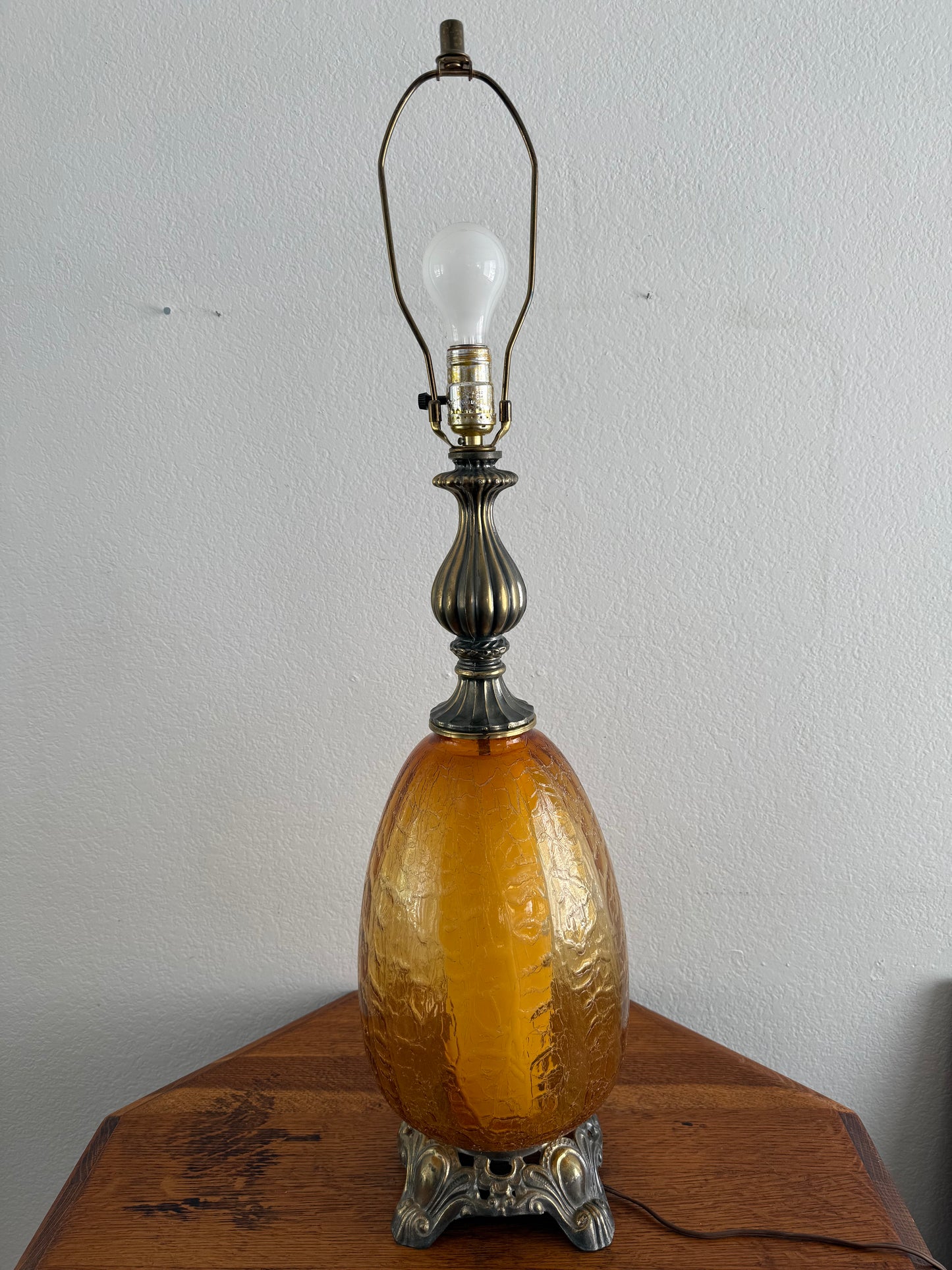 Decorative crackle glass lamp with a brown glass bulb on a wooden base against a white wall.