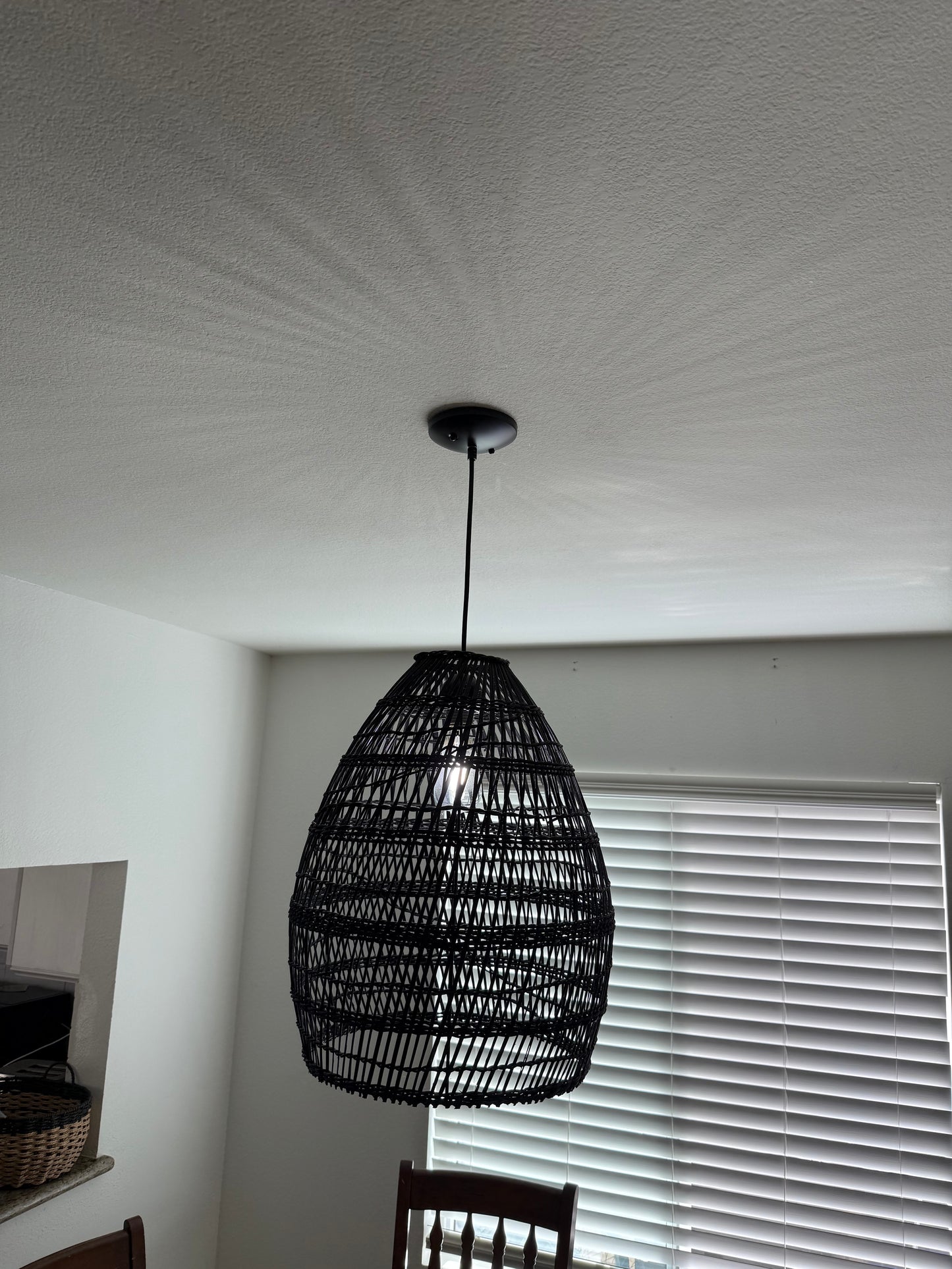 Black woven wall light fixture on a white wall