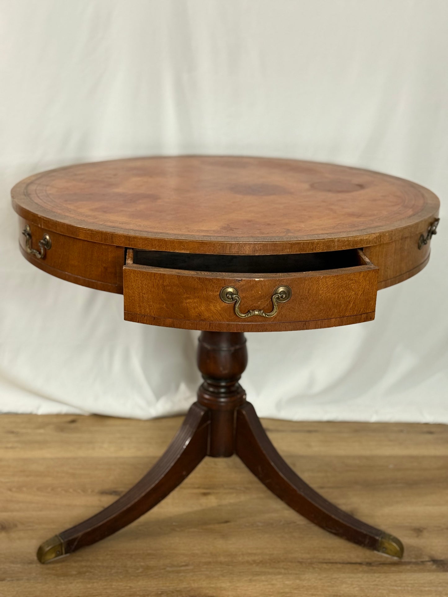 Round wooden table with a single drawer on a plain background