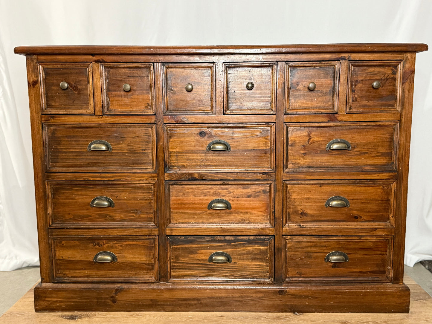 Wooden dresser with multiple drawers and metal handles on a white background