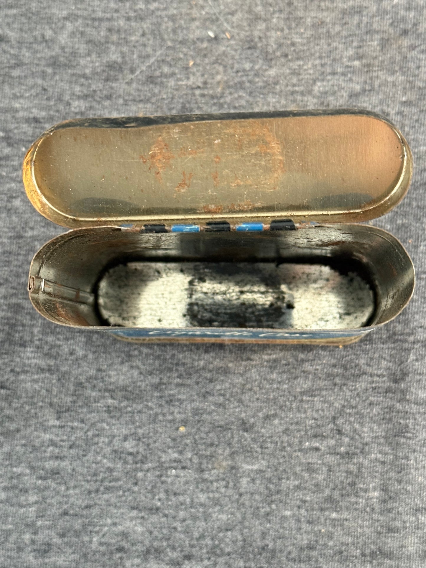 Open metal case with worn interior on a textured gray background