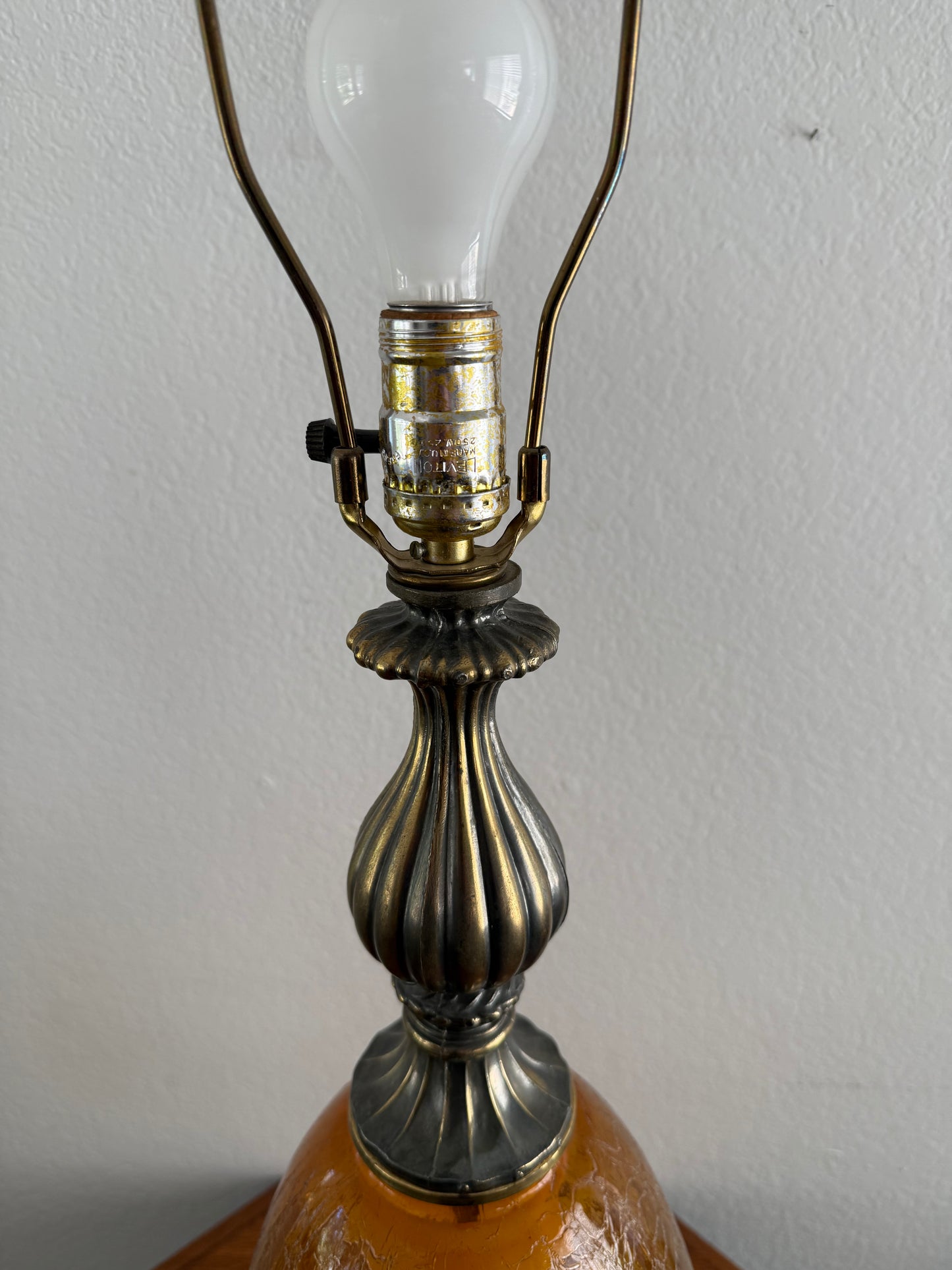 Close-up of a lamp with a decorative metal fitting and light bulb on a plain background