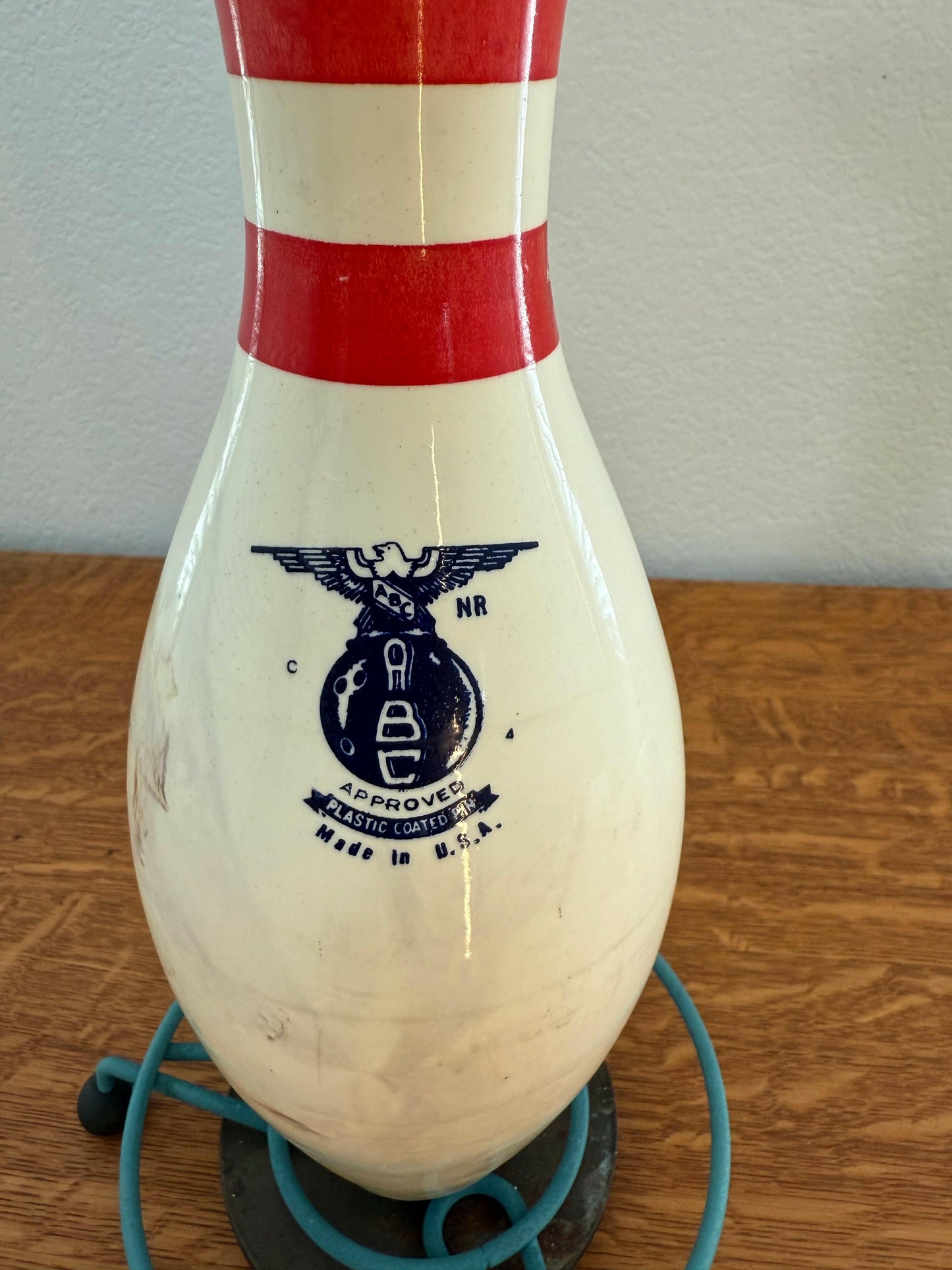 Bowling pin with red and white stripes on a wooden floor