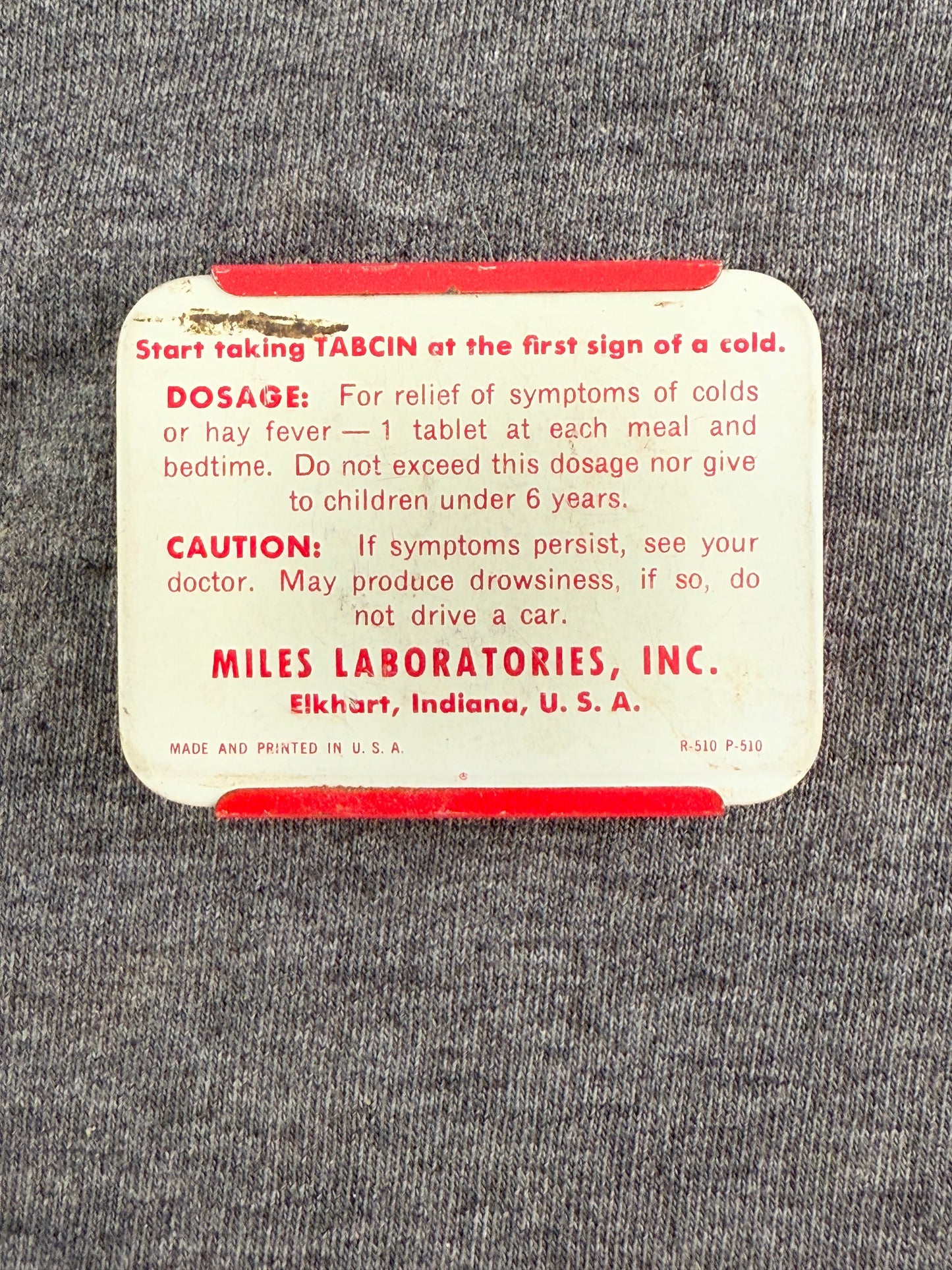 Vintage medication package with red text on a gray textured background