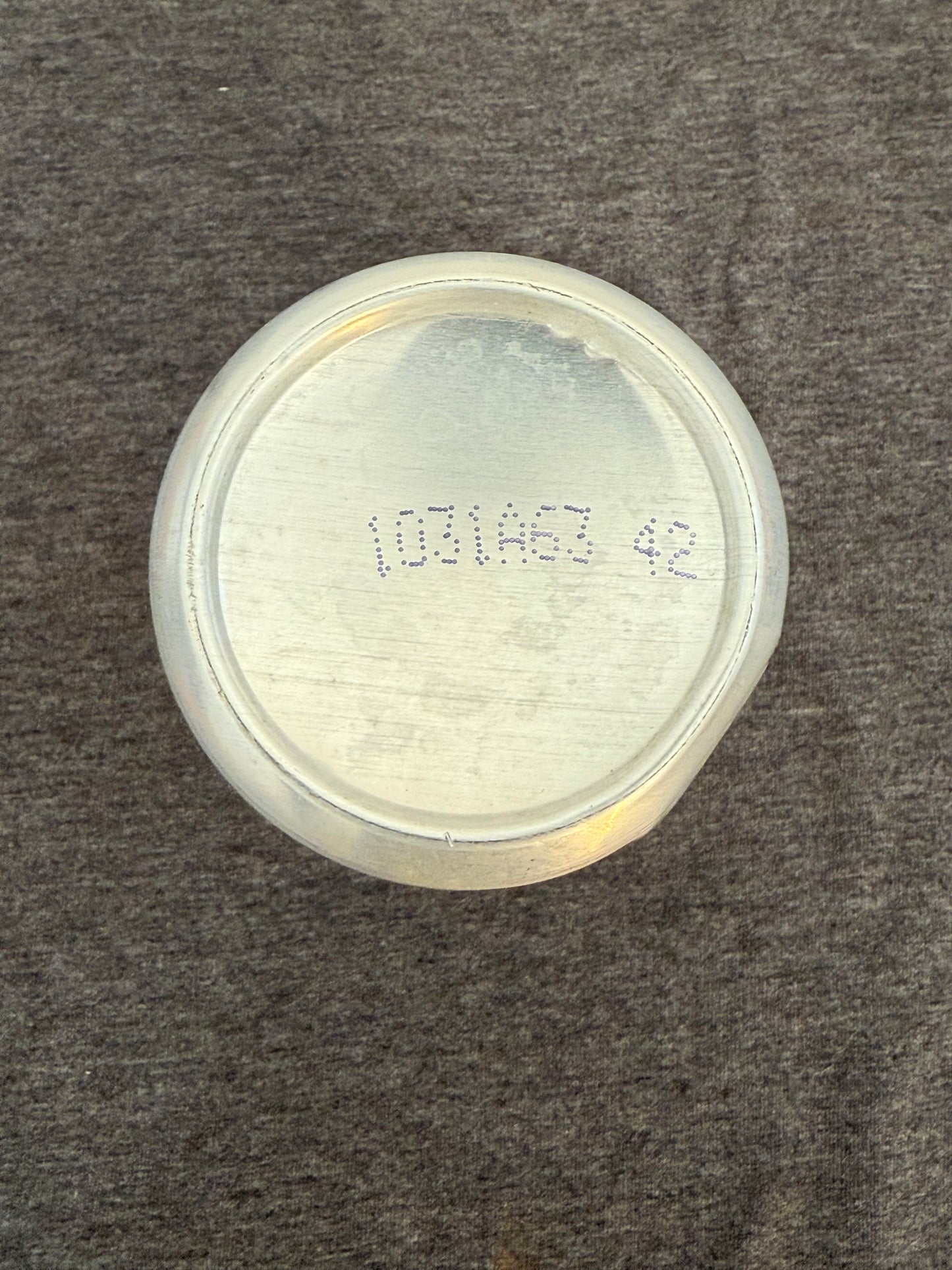 Silver circular object with text on a gray textured background