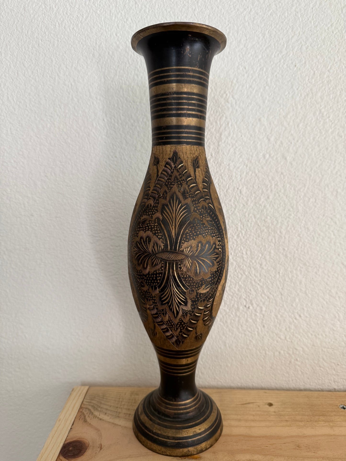 Decorative vase with intricate carvings on a white wall.