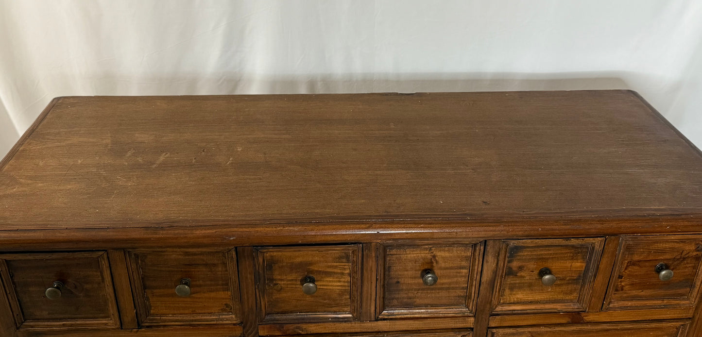 Wooden dresser with multiple drawers against a white background