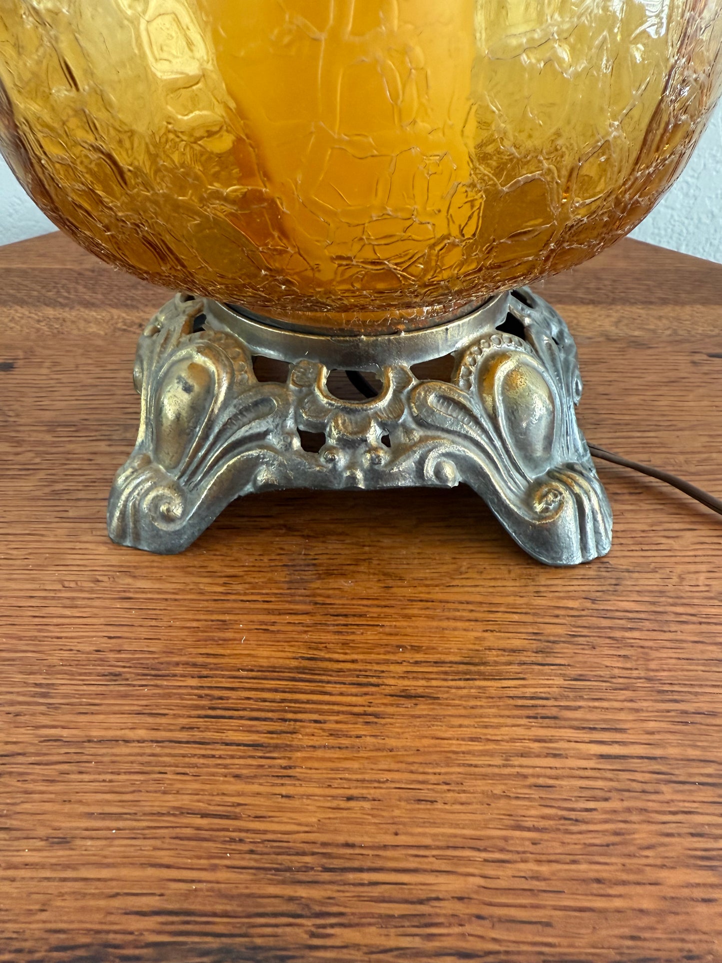 Decorative amber glass ornament with intricate metal fixture on a wooden surface