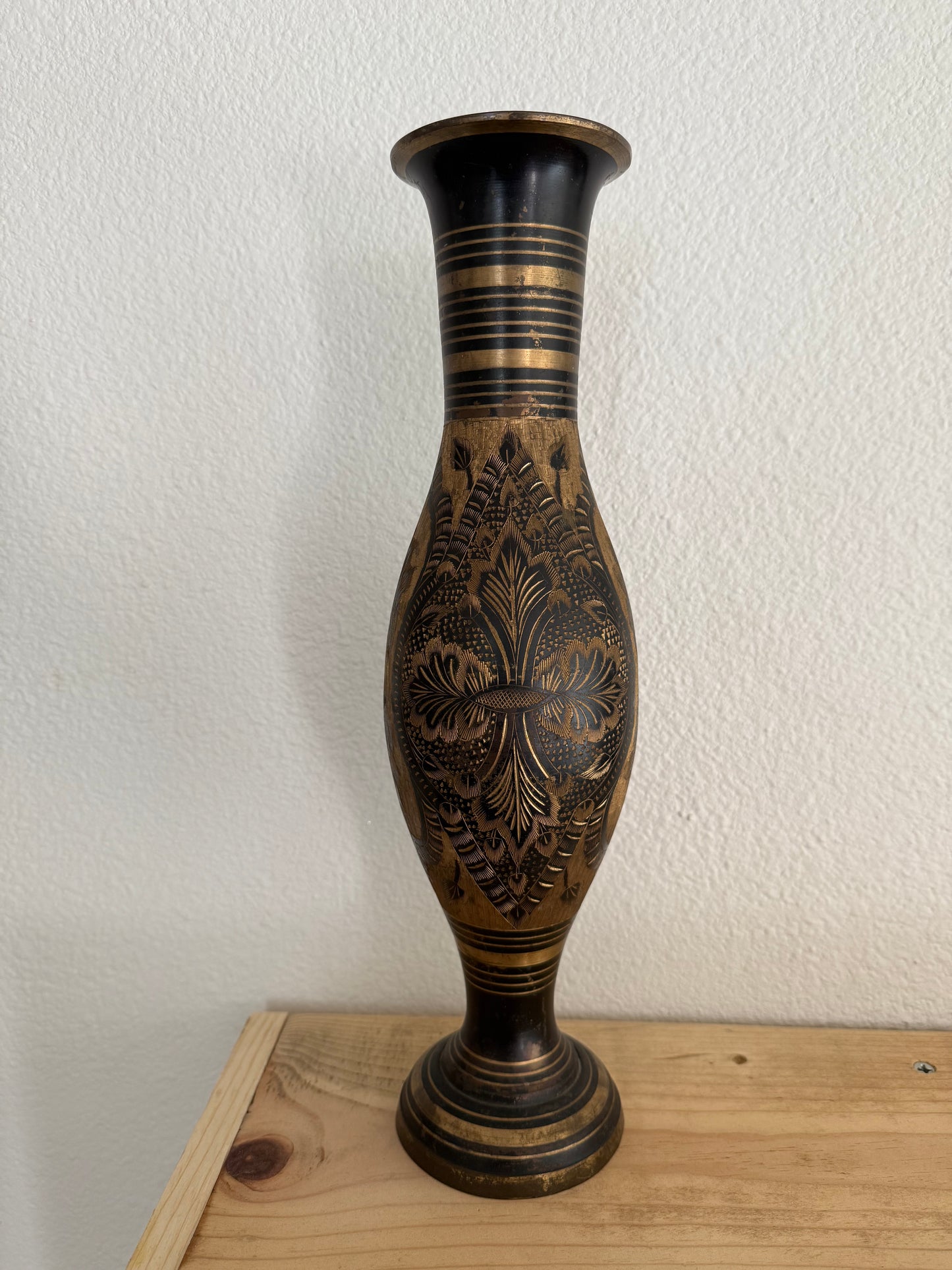 Decorative vase with intricate carvings on a white wall.