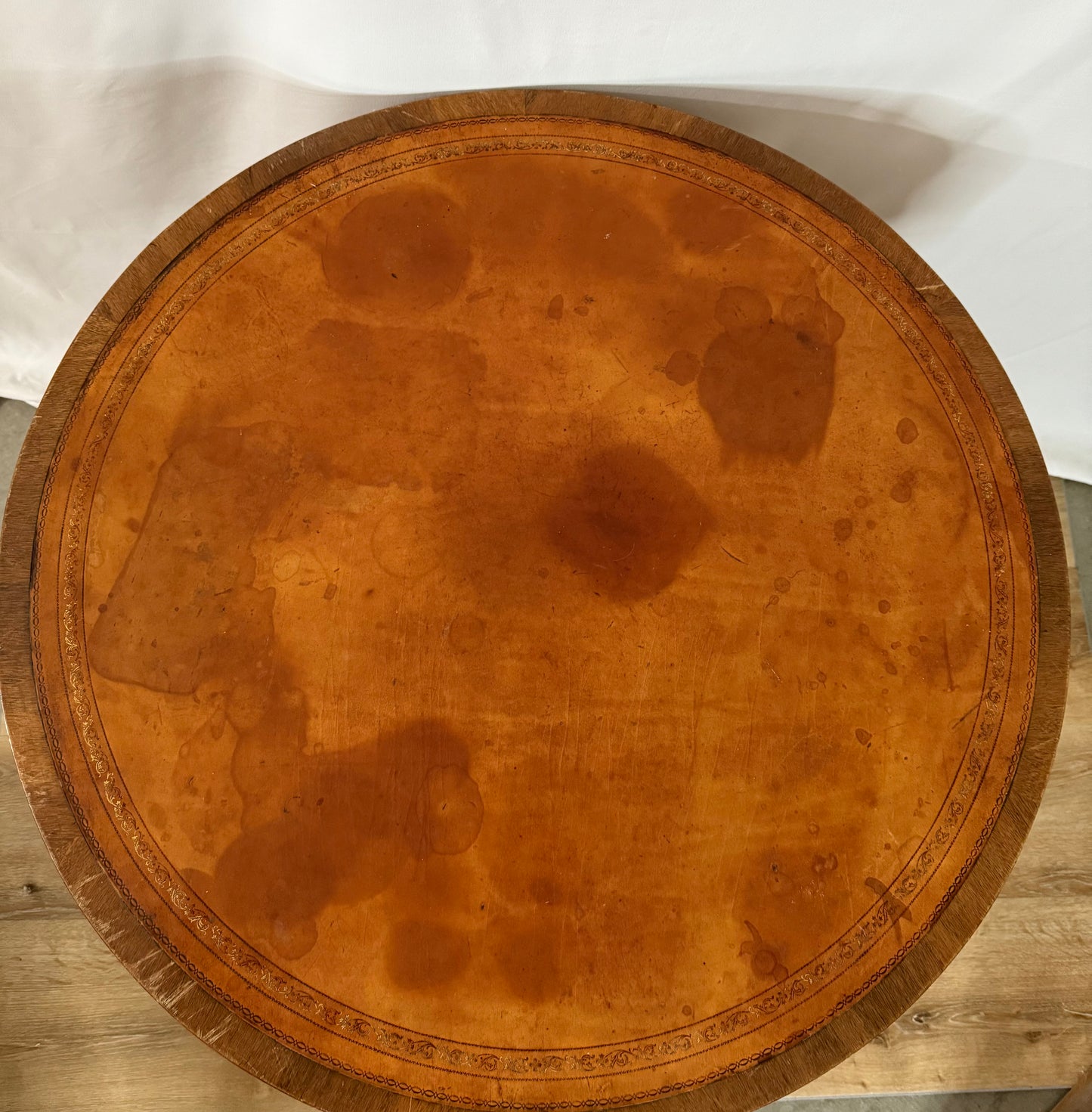 Round wooden table with a brown leather top on a white background