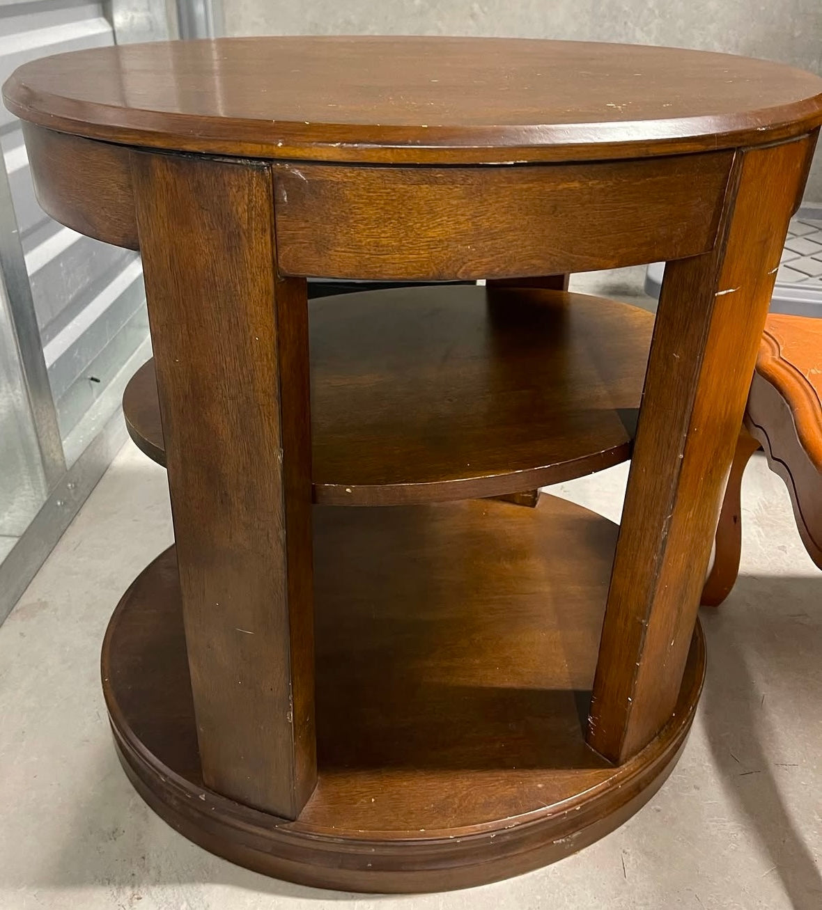 Wooden round table with shelves on a neutral background