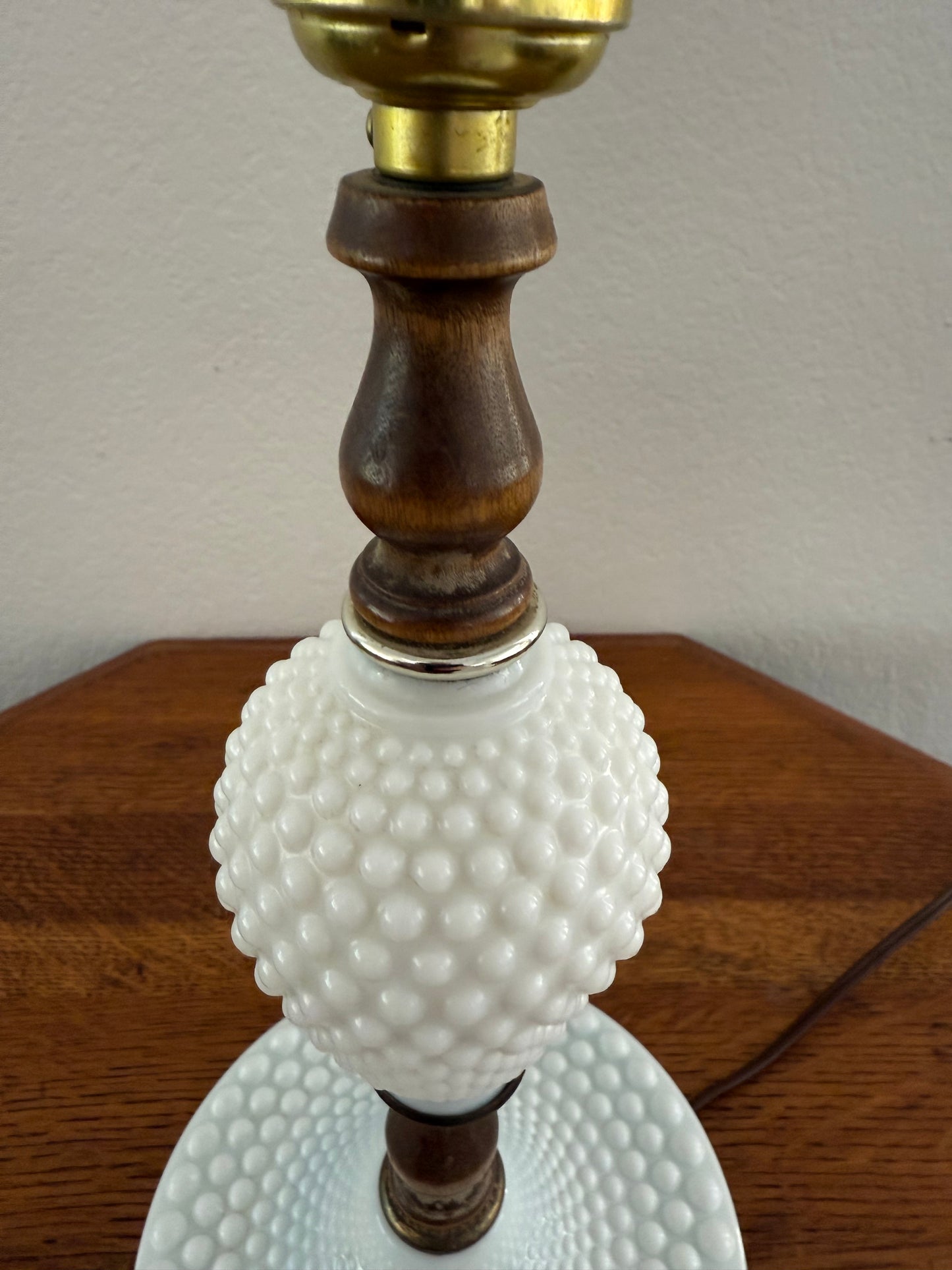 Decorative lamp with white textured shade, wooden base, and brass fitting.