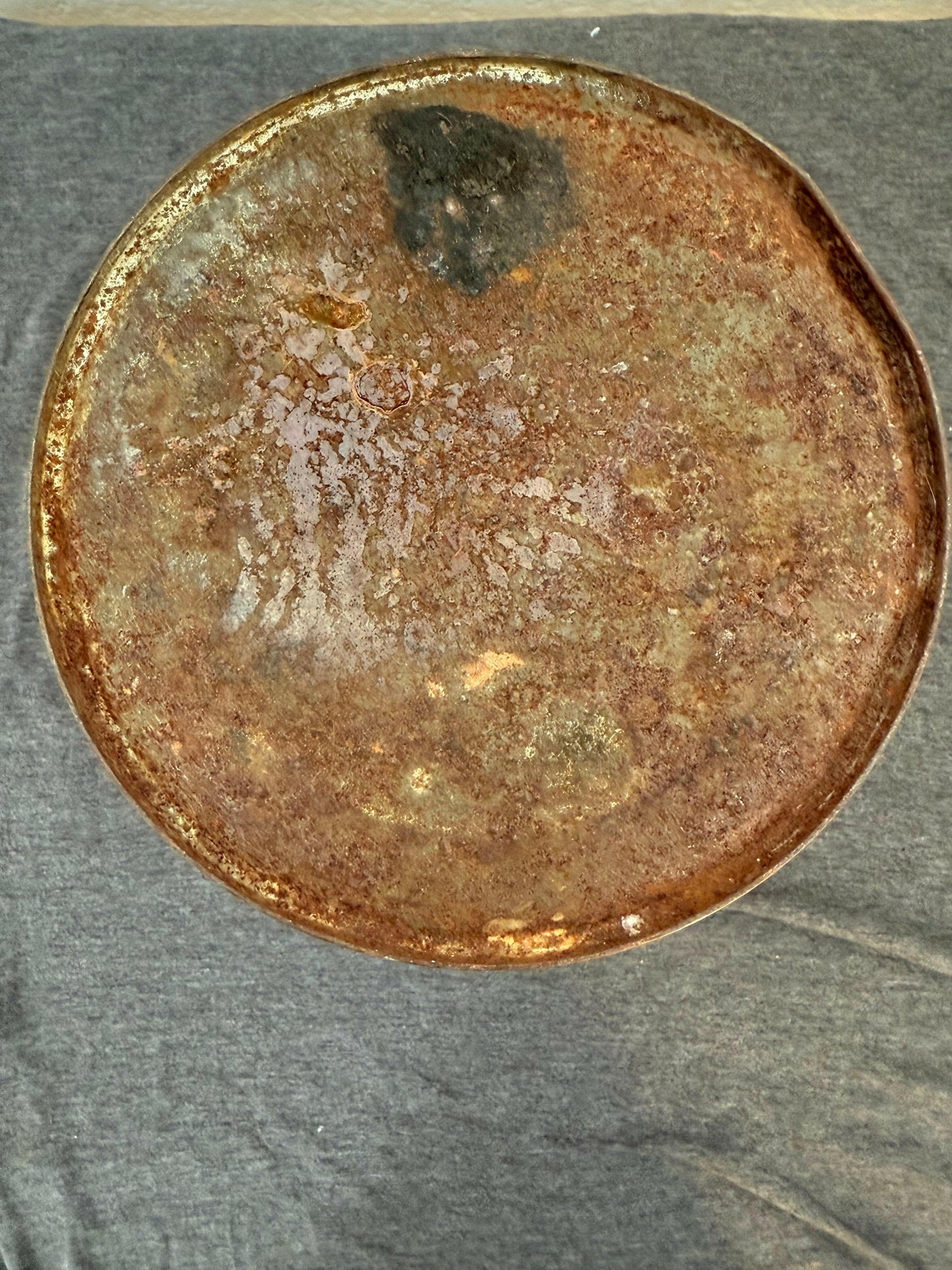 Rust-covered metal disc on a textured gray background