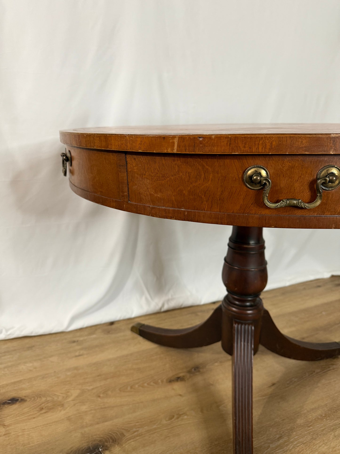Wooden side table with round top and curved legs on a white surface.
