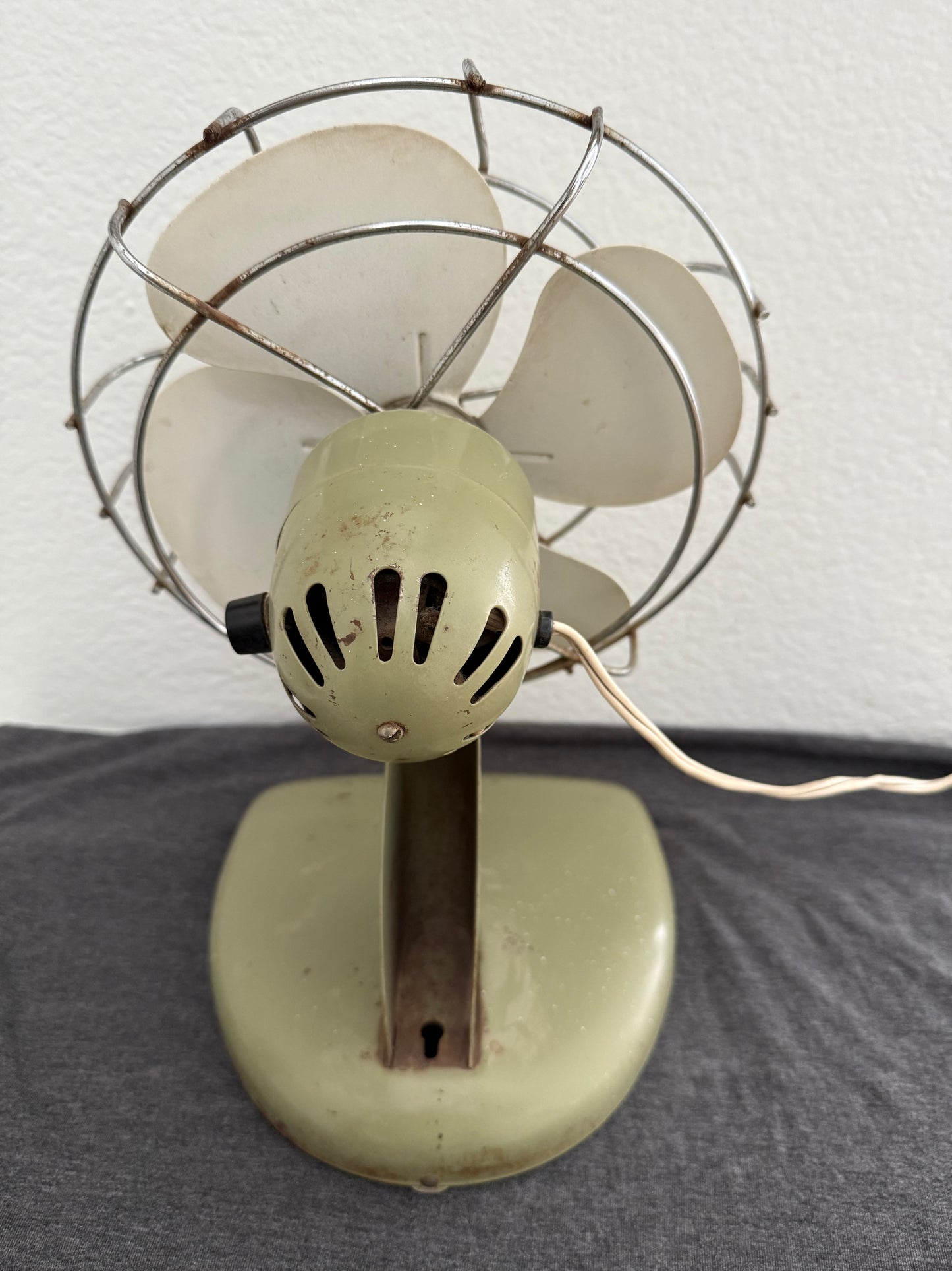 Vintage-style desk fan with white blades and metal frame against a neutral background