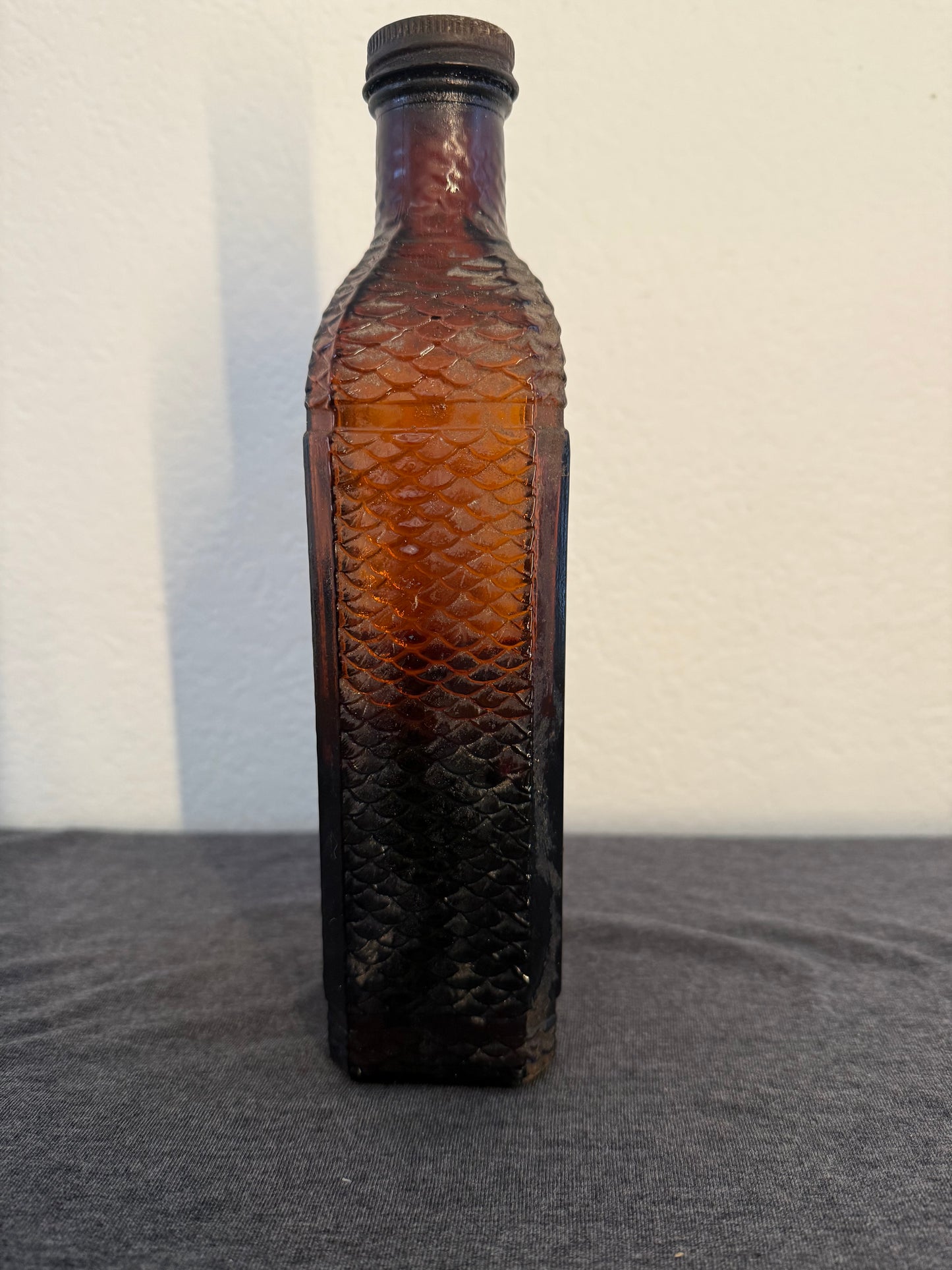 Brown glass bottle with textured surface on a light gray background