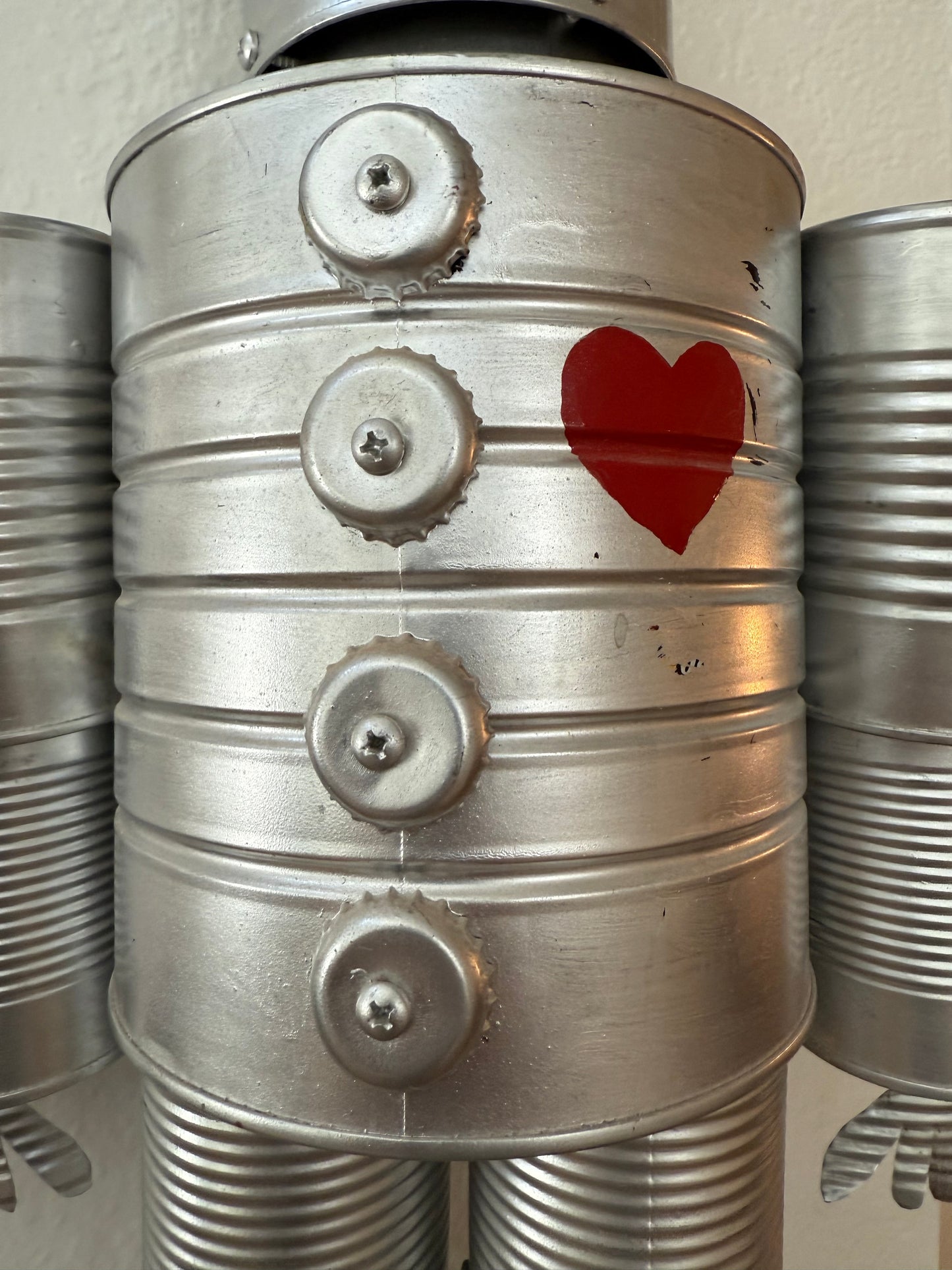 Metallic cylindrical object with a red heart symbol on a beige background