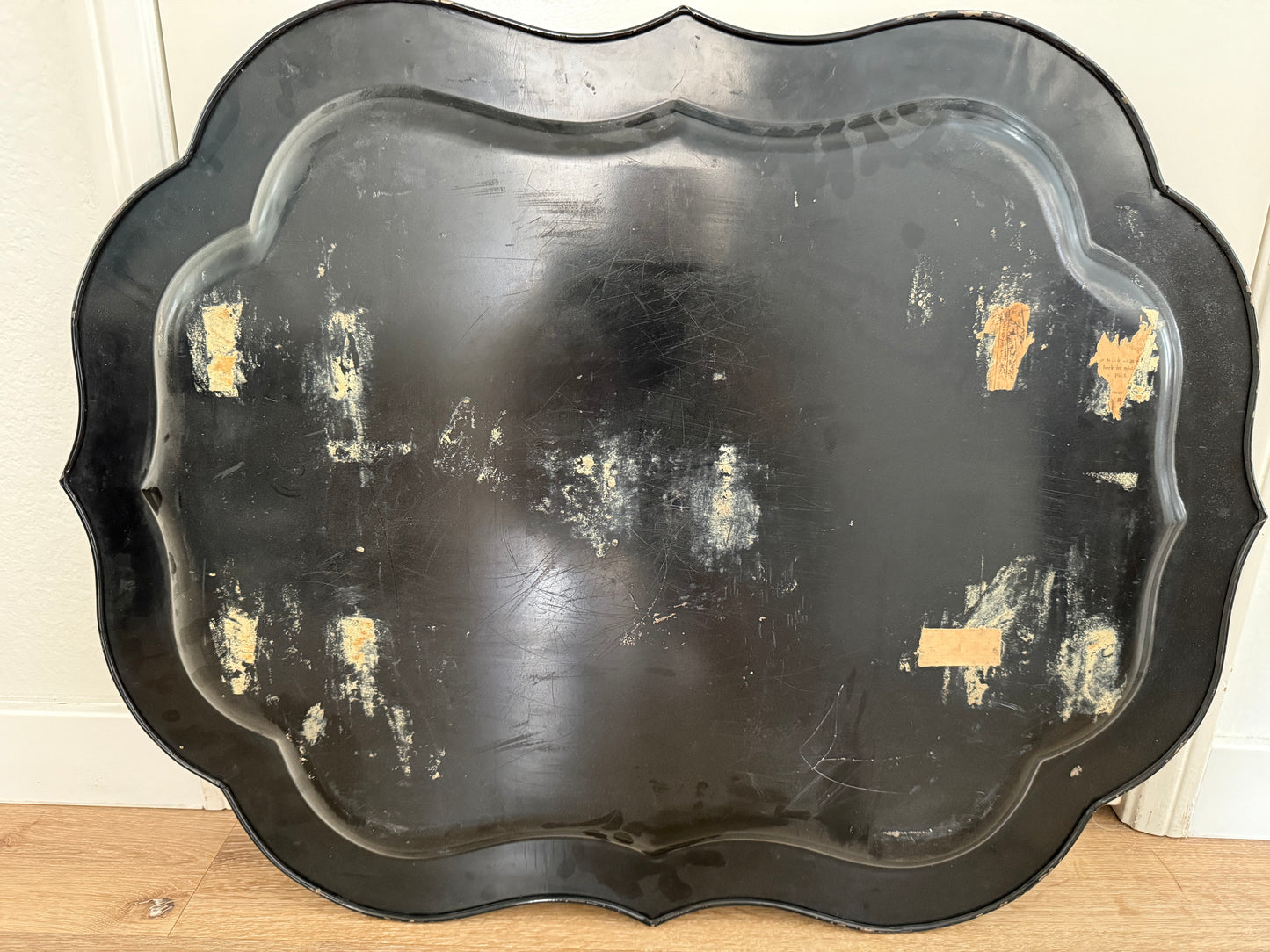 Black decorative tray with gold accents on a wooden surface