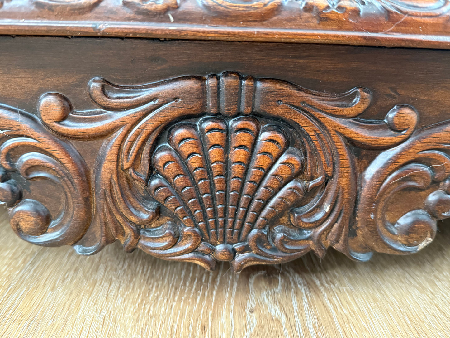 Close-up of a wooden surface with intricate carvings, including a shell design.