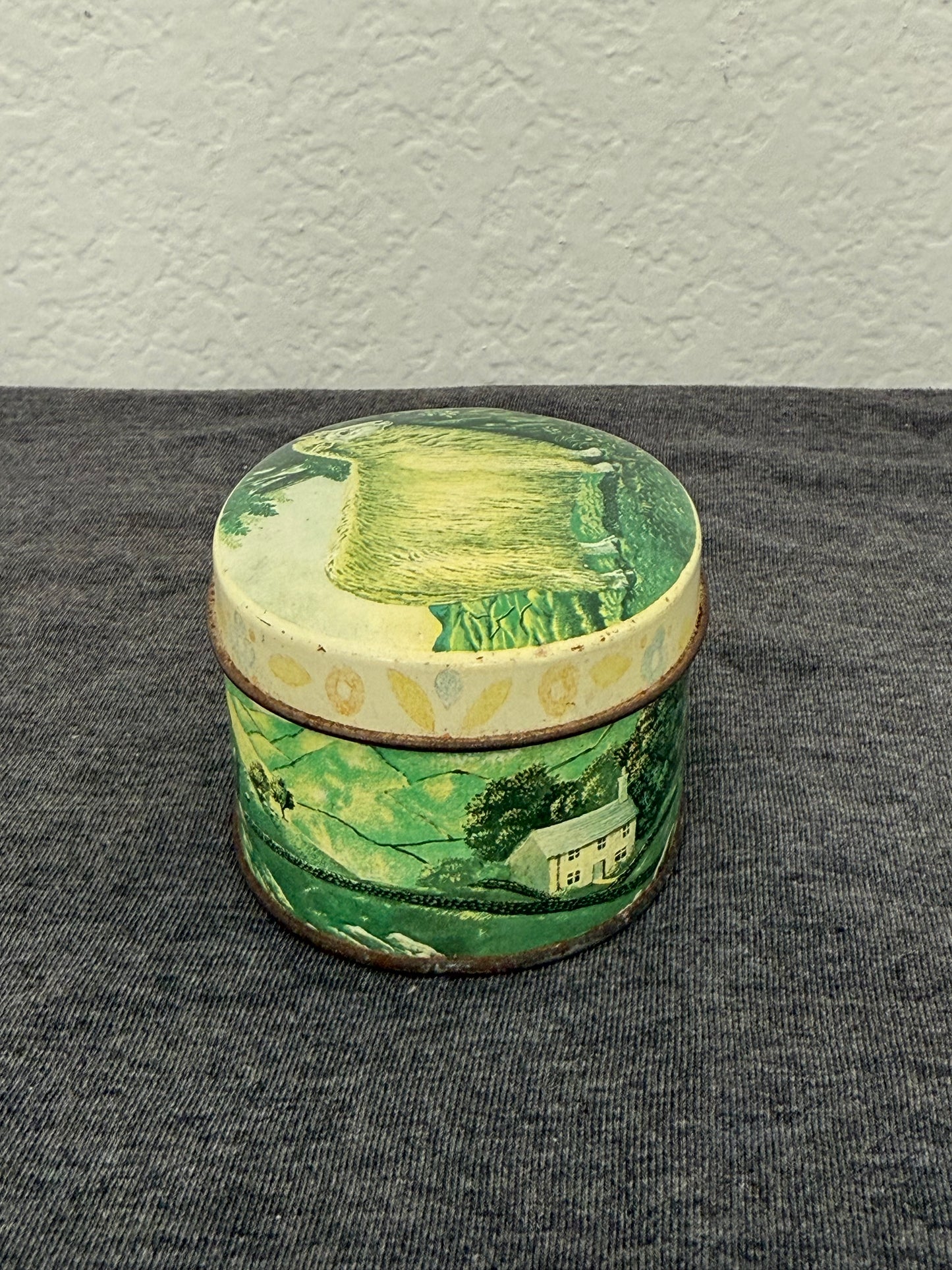 Small cylindrical container with green and white design on a gray background