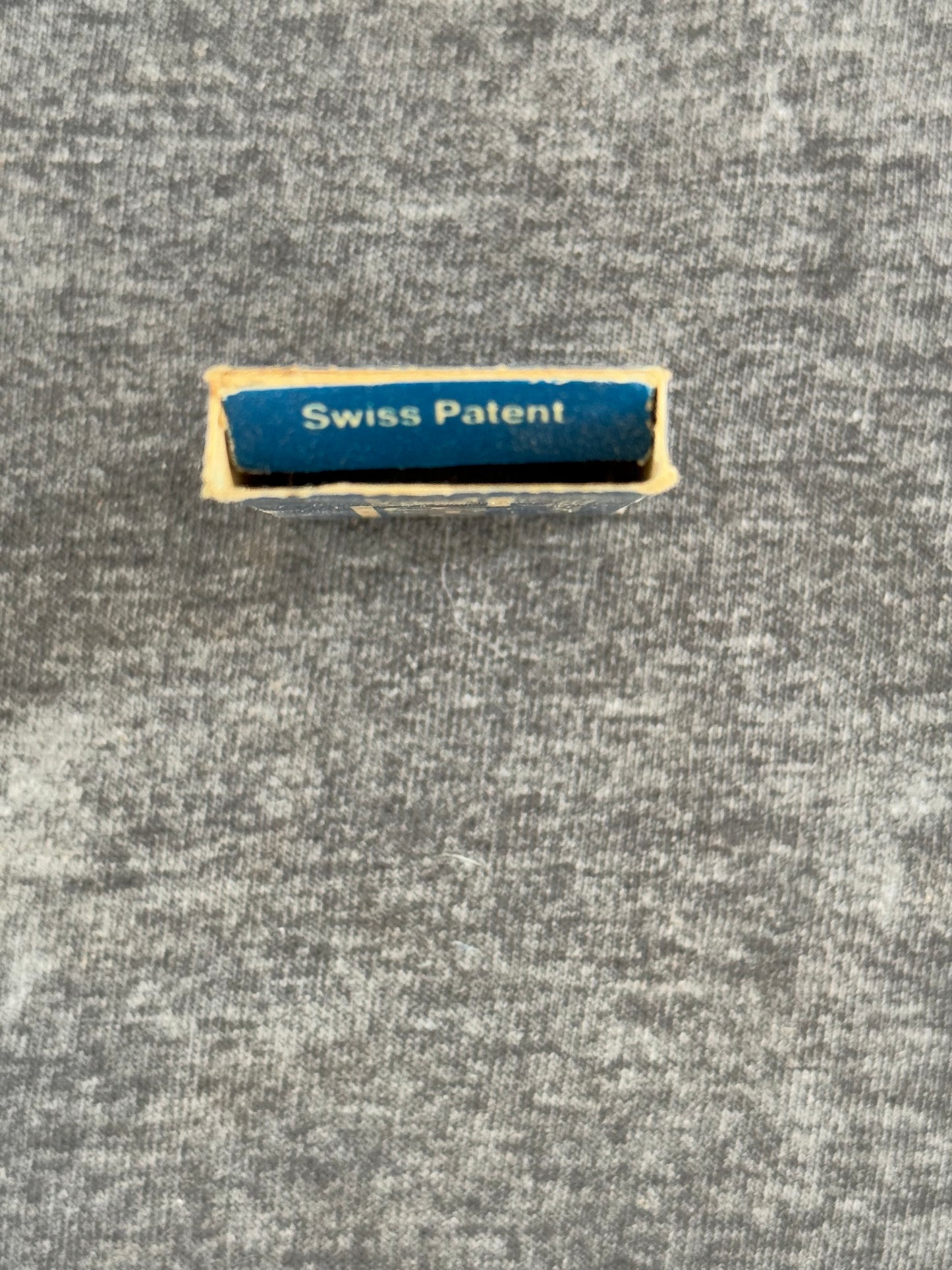 Rectangular 'Swiss Patent' label on a textured gray background