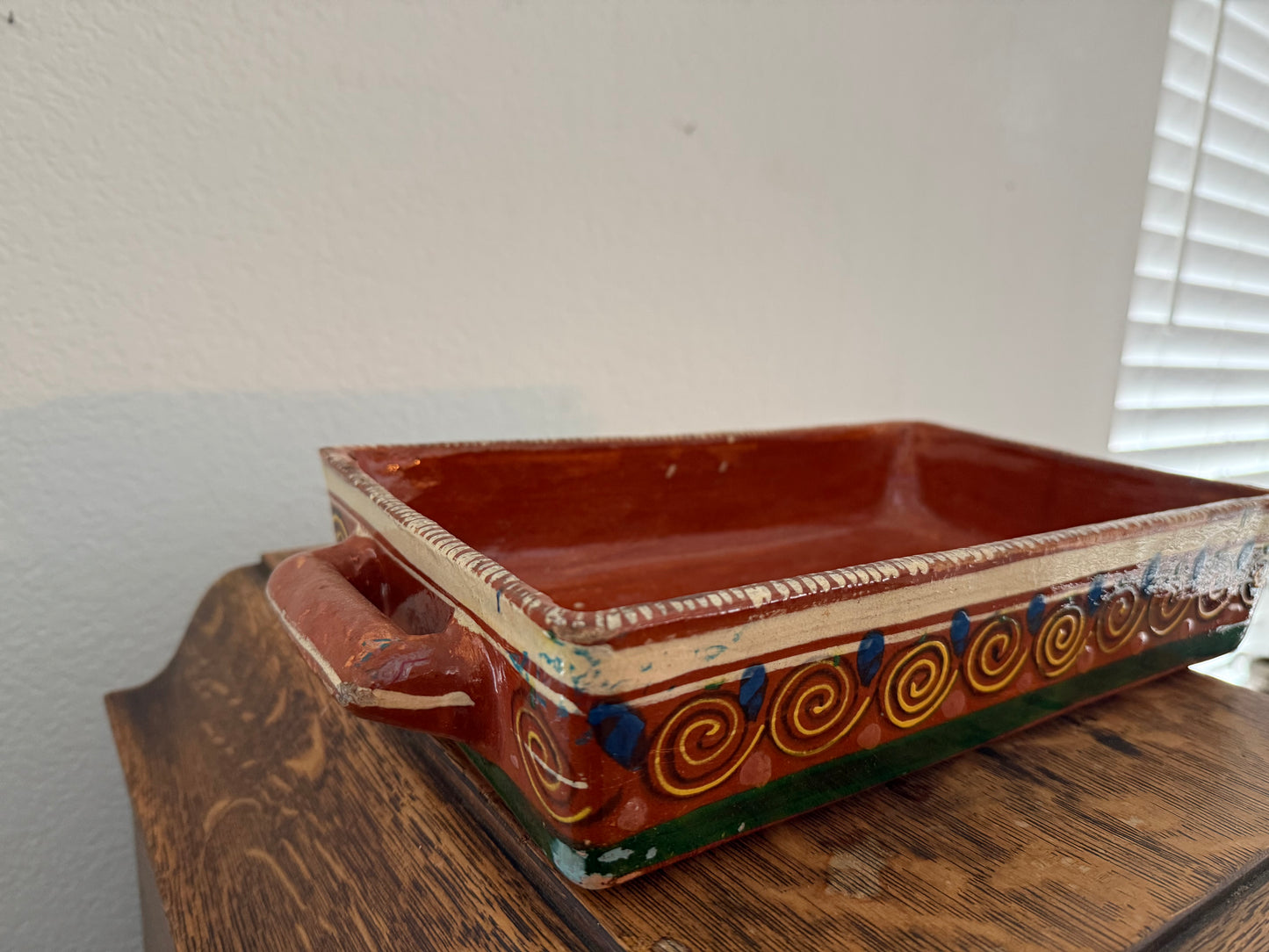 Decorative ceramic tray with handles on a wooden surface