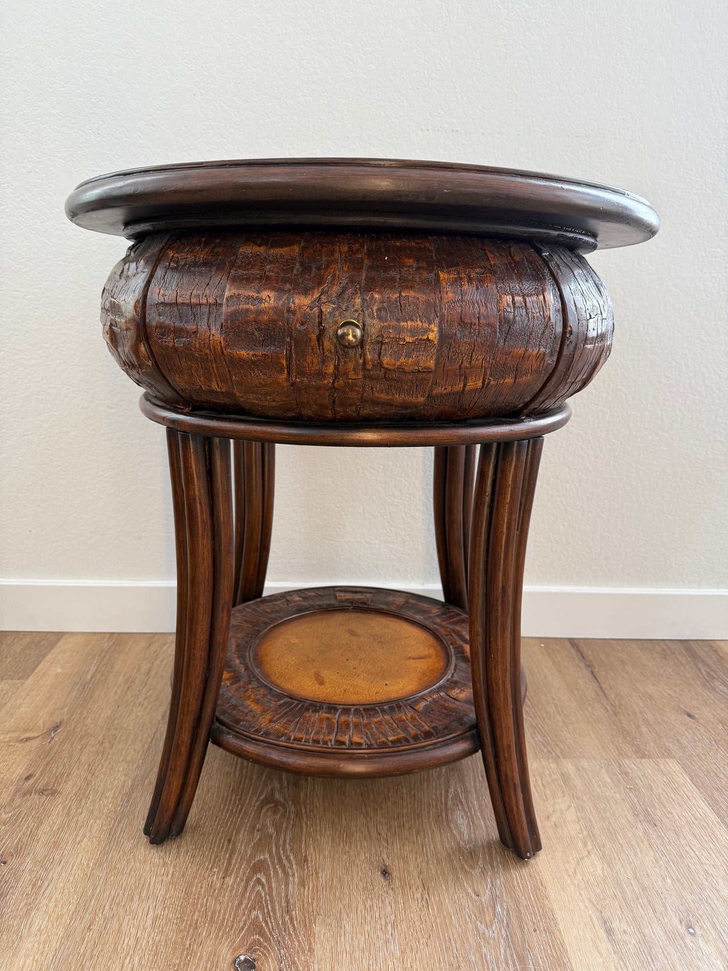 Round side table with a textured surface and a shelf on a wooden floor.