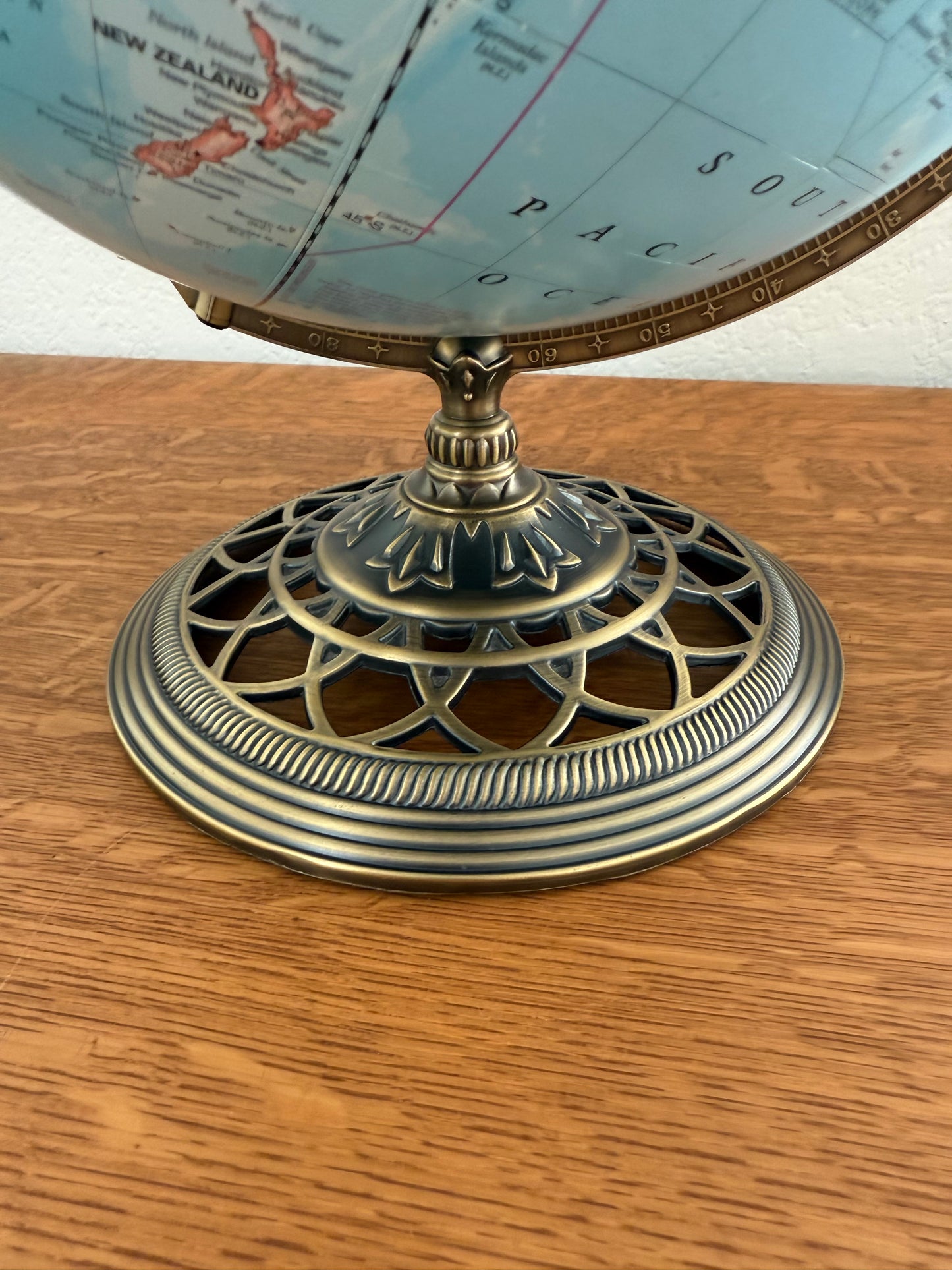 Vintage-style globe with decorative base on a wooden surface