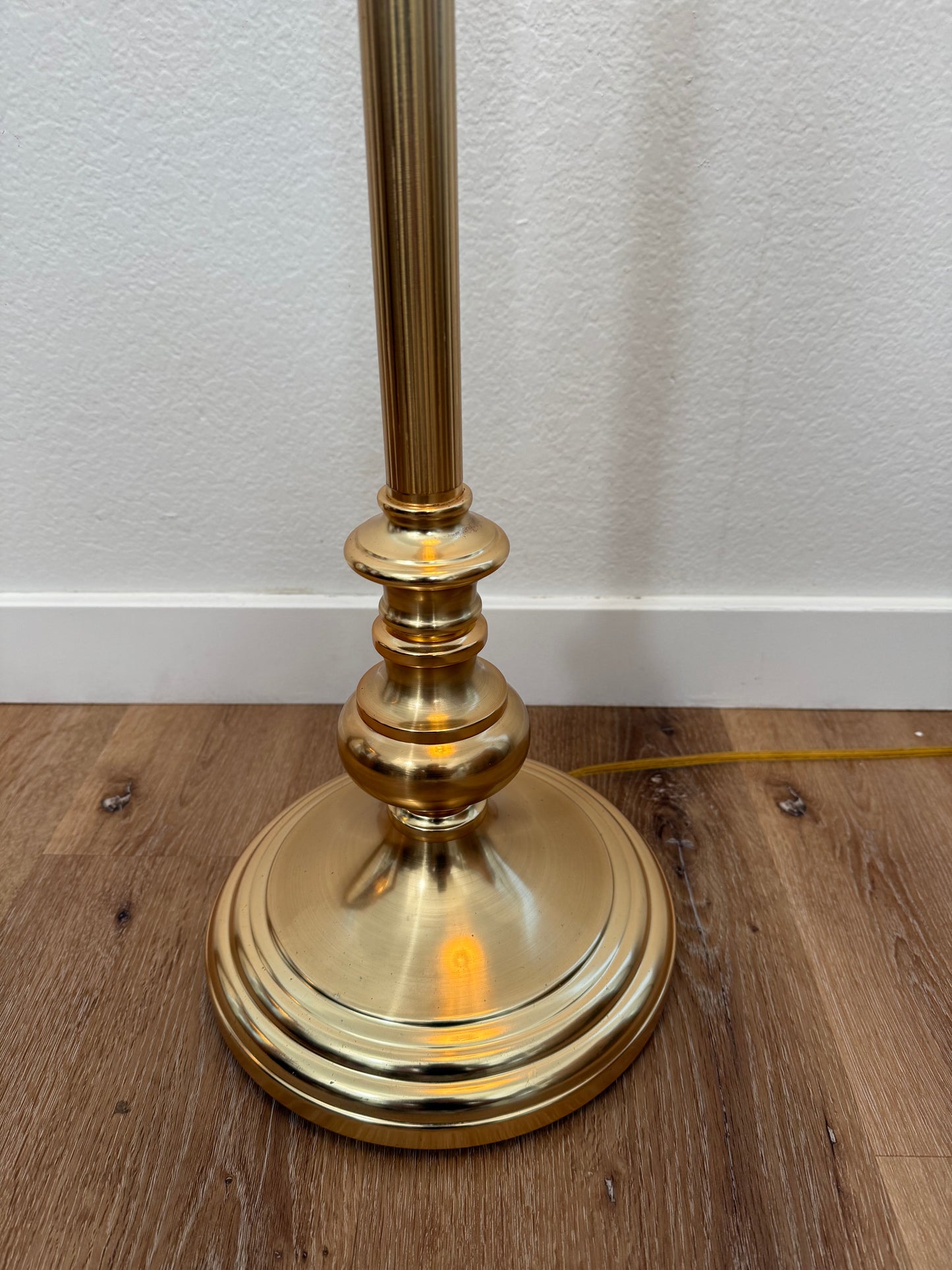 brass base on wood floor with a white wall background