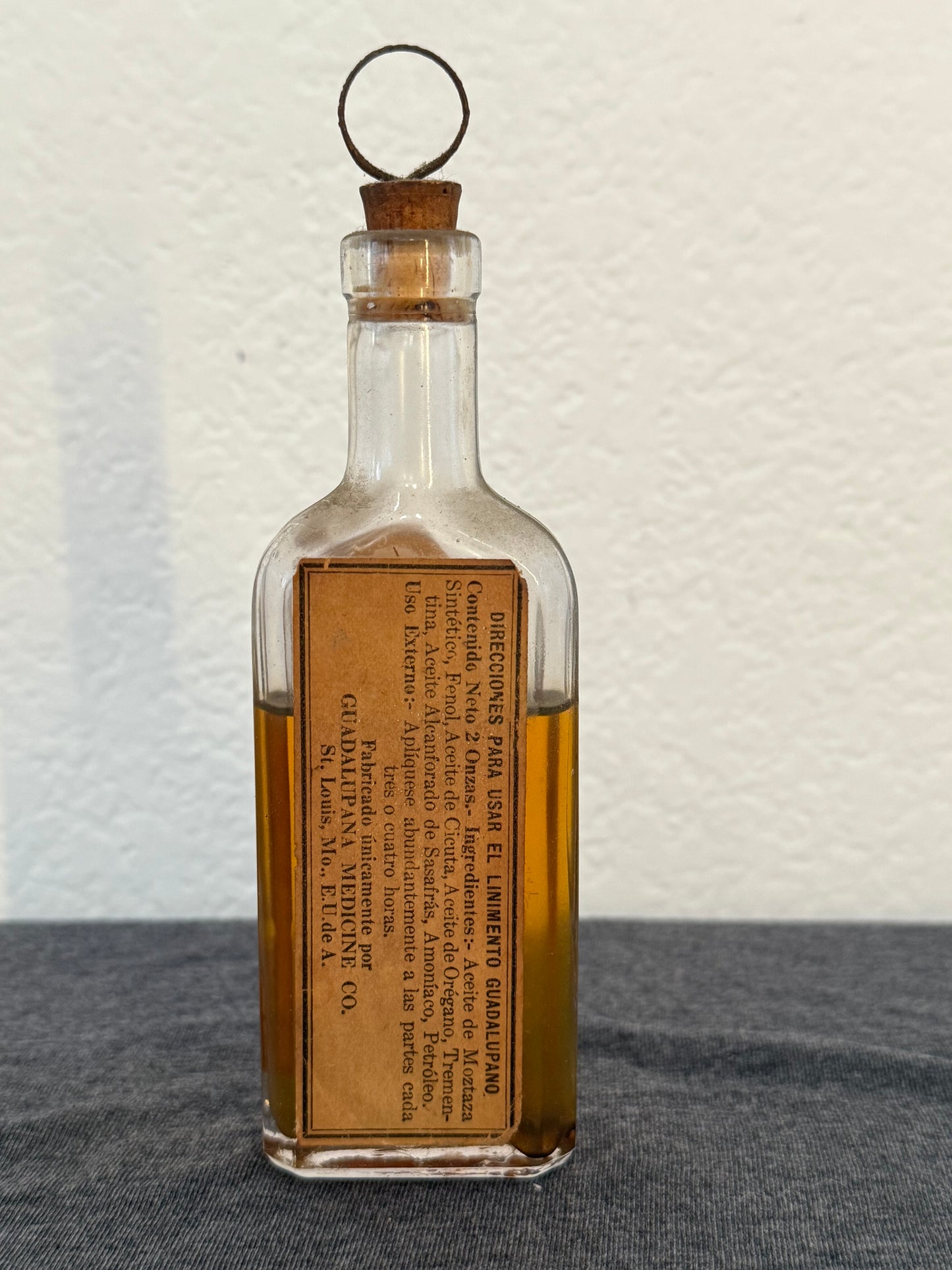Vintage glass bottle with wooden cork and label on a textured surface