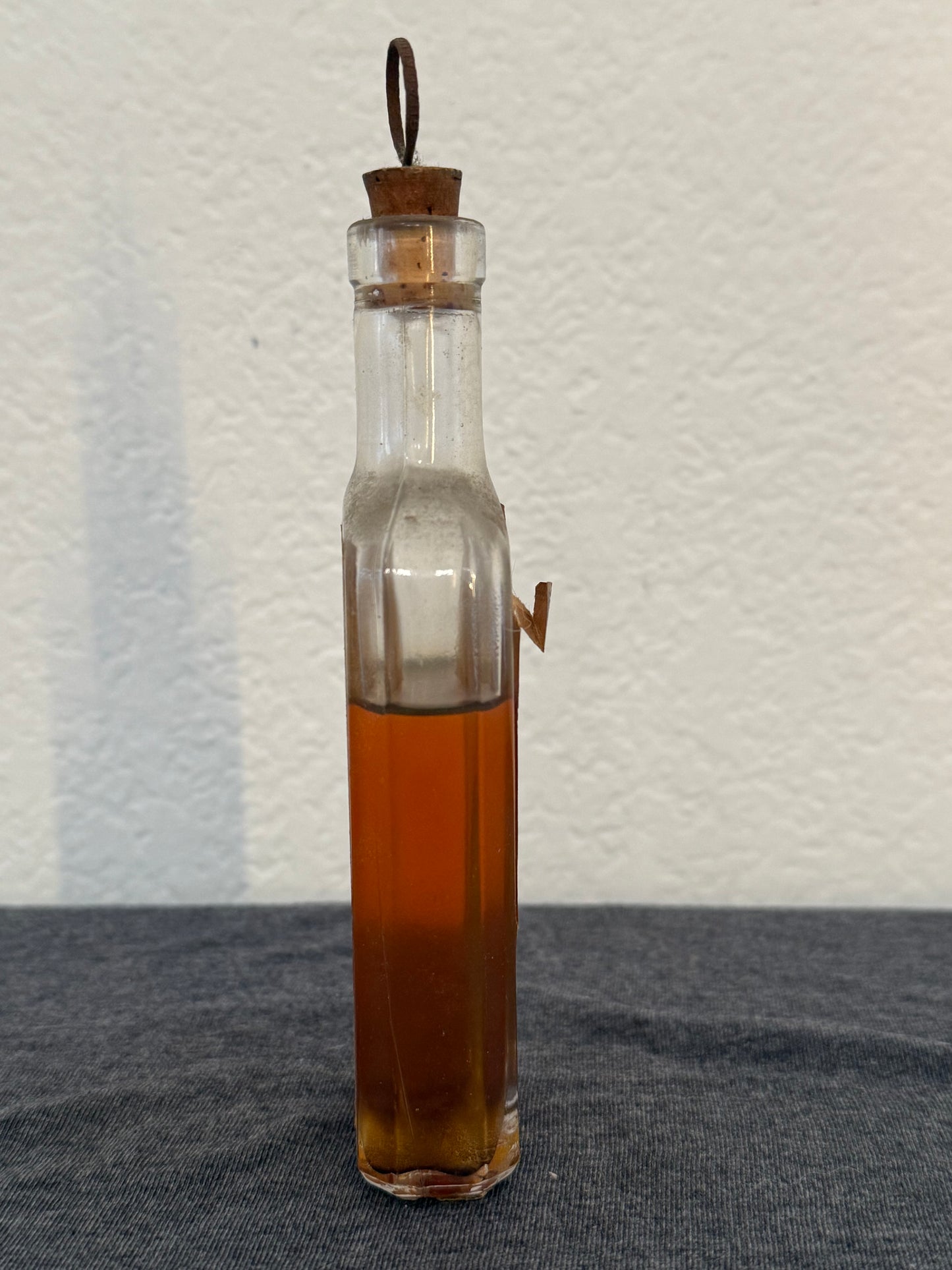 Clear glass bottle with brown liquid on a textured surface
