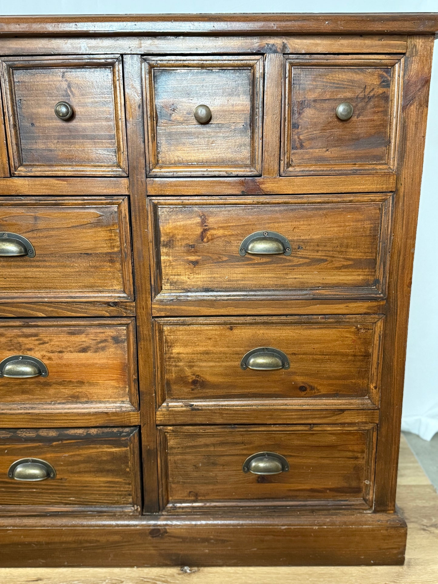 Wooden dresser with multiple drawers and metal handles on a light background