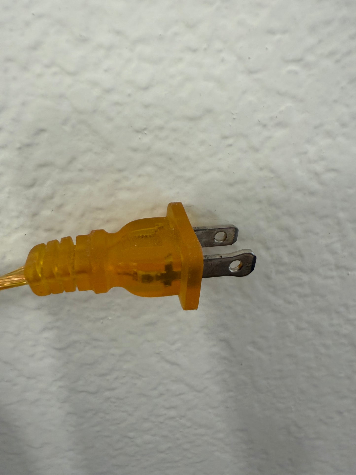 Yellow electrical plug on a textured white background