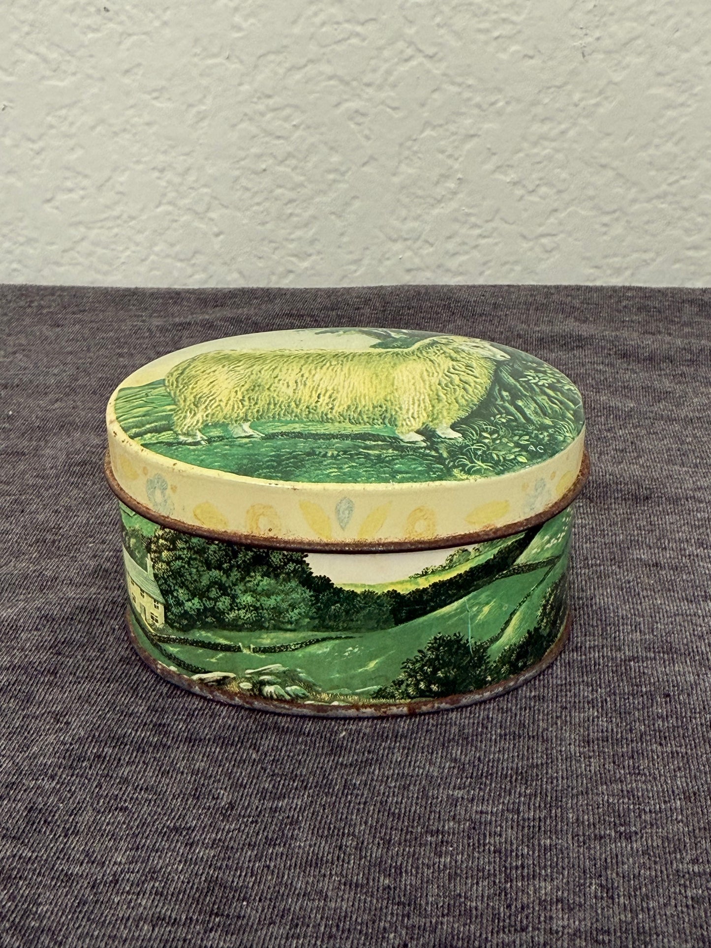 Round decorative item with green landscape design on a gray surface
