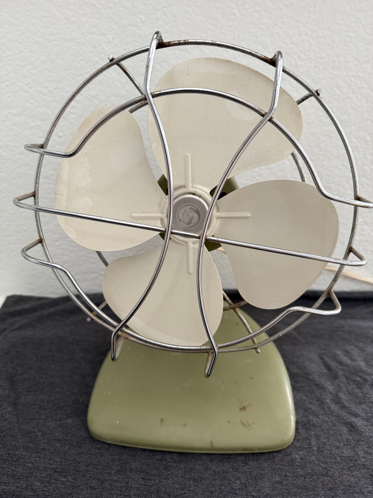 Vintage-style desk fan with white blades and metal frame against a neutral background