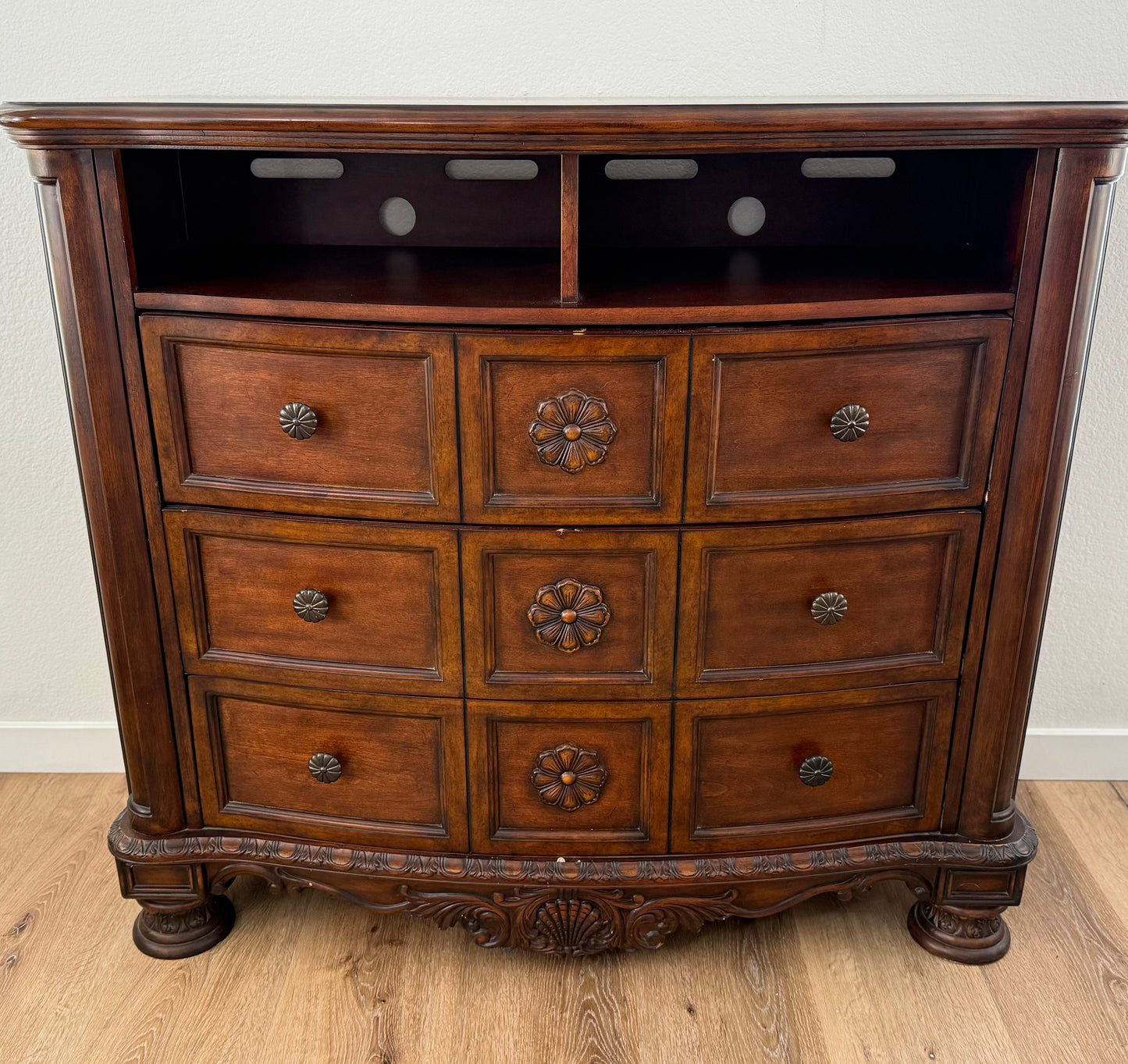 Wooden dresser with multiple drawers on a wooden floor.