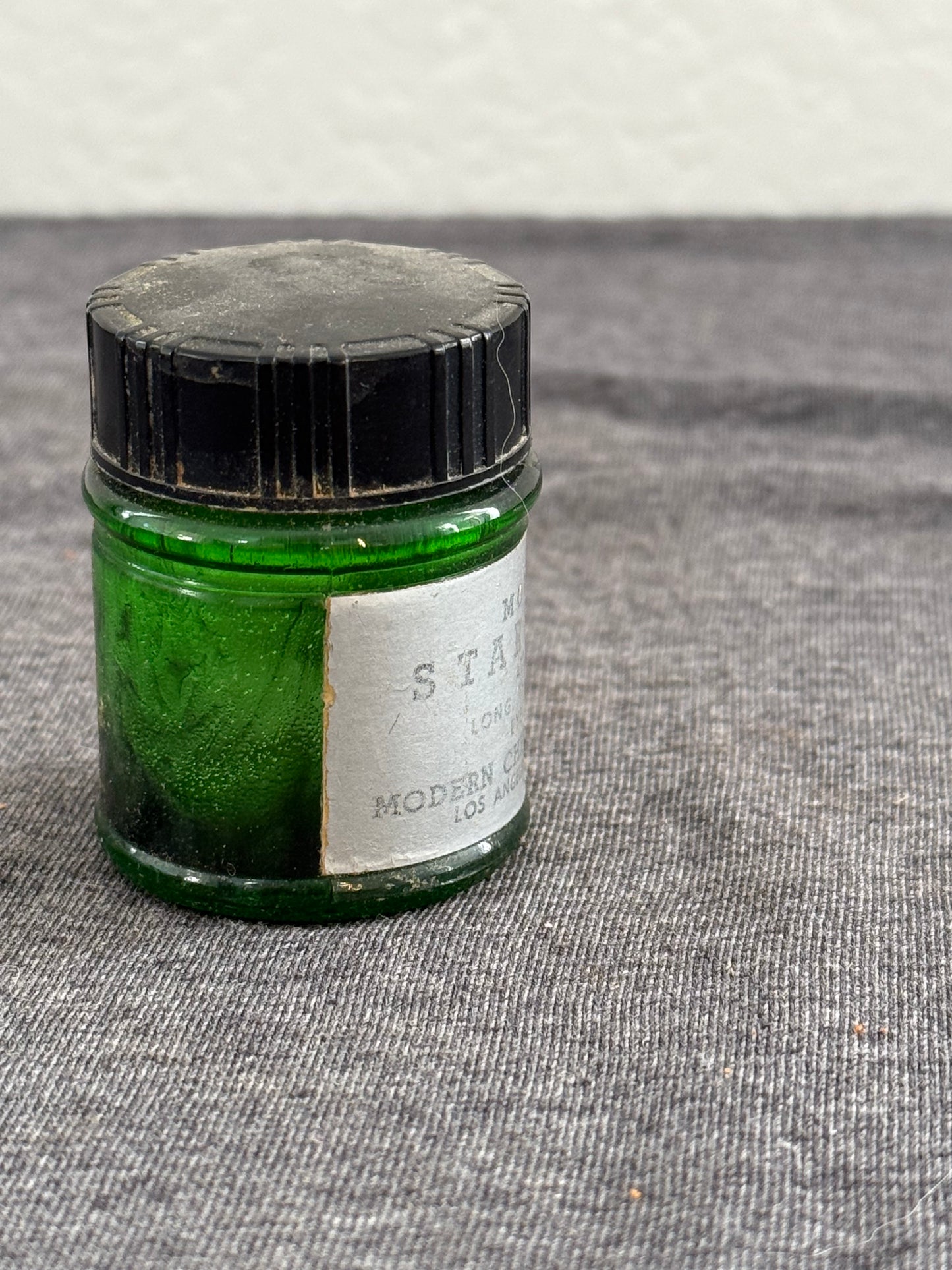 Small green jar with a label on a textured surface