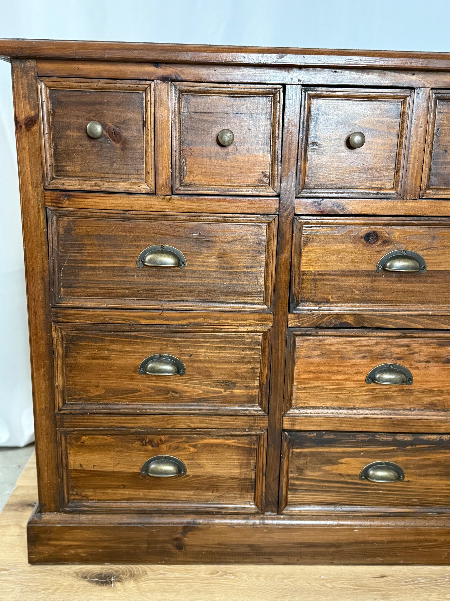 Wooden dresser with multiple drawers and metal handles on a light background