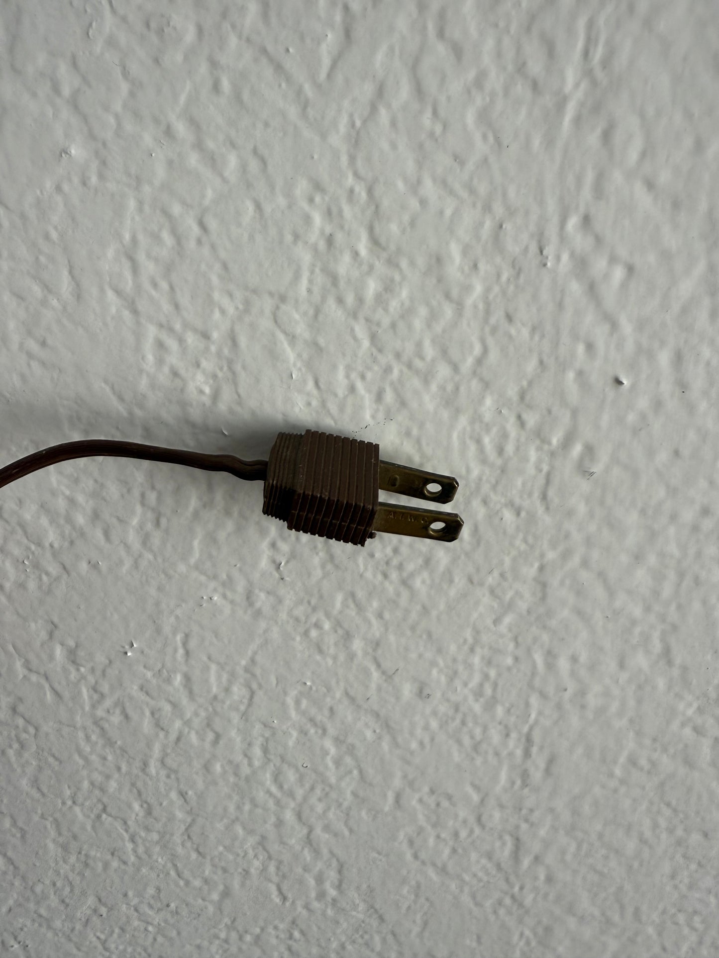 Old-style electrical plug on a textured white surface