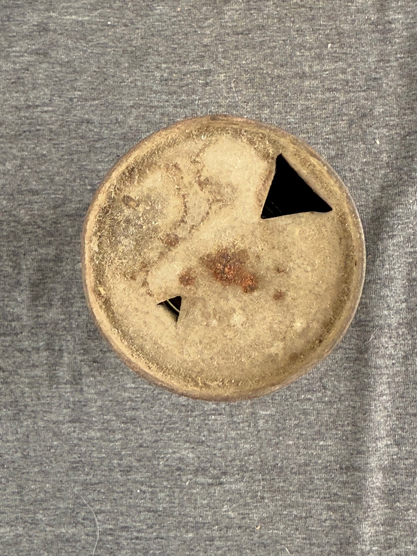 Round metallic object with two black arrows on a gray background