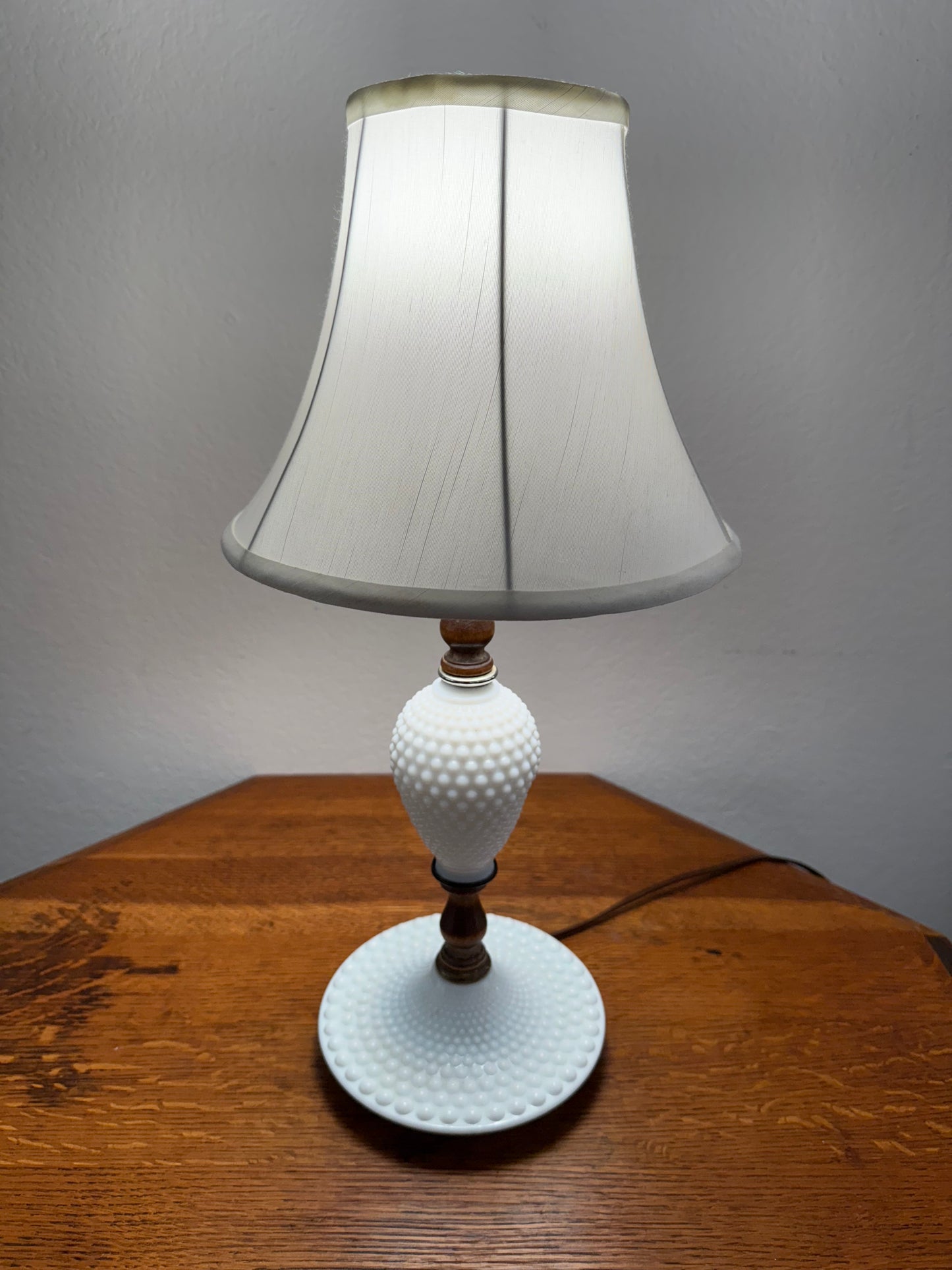 Lamp with white textured base and gray shade on a wooden surface