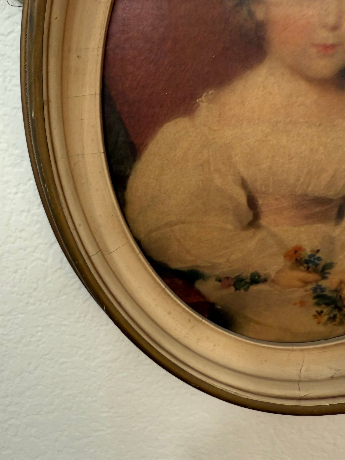 Round painting with decorative frame on a textured wall