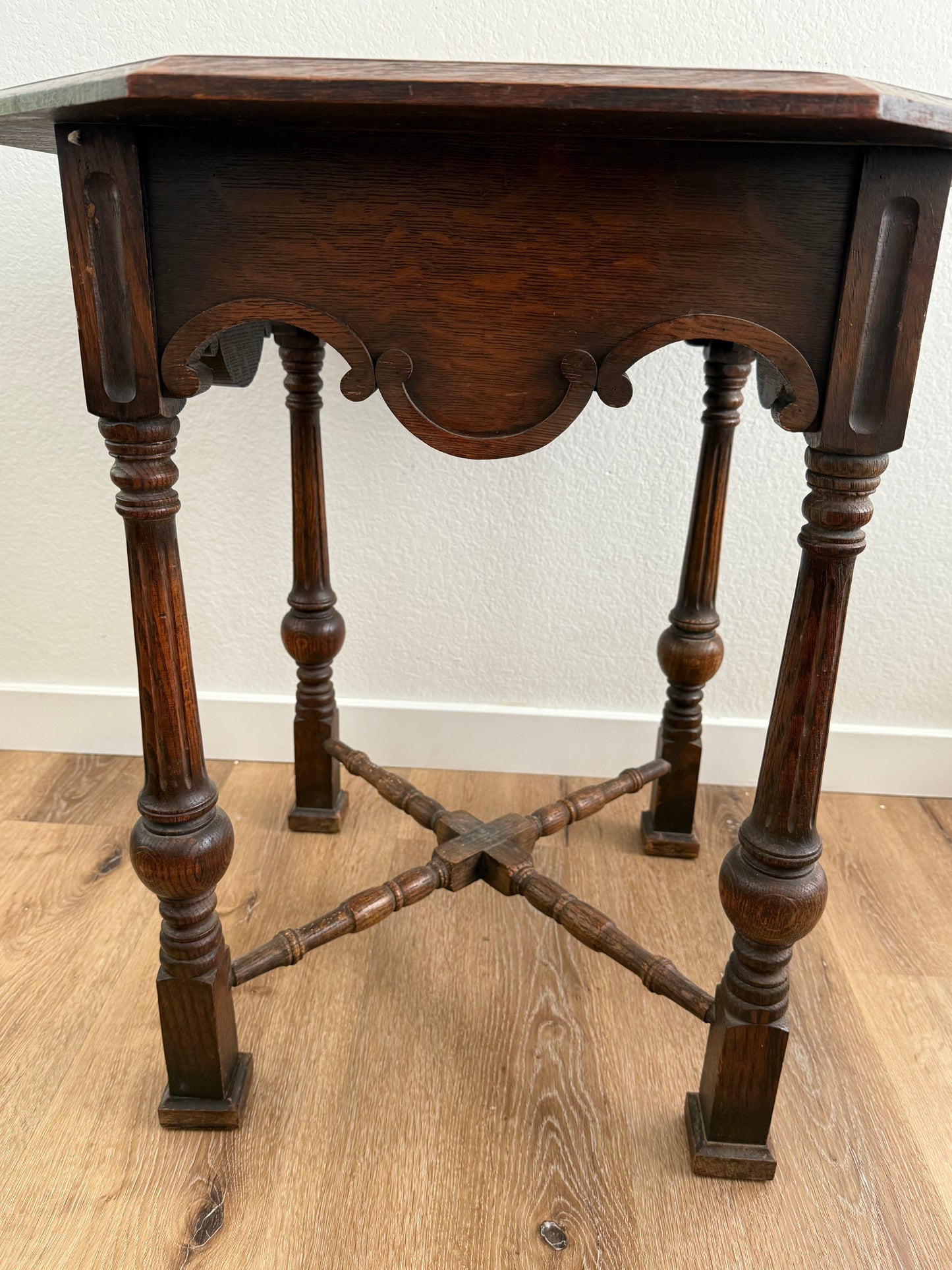 Wooden side table with intricate design on a wooden floor.