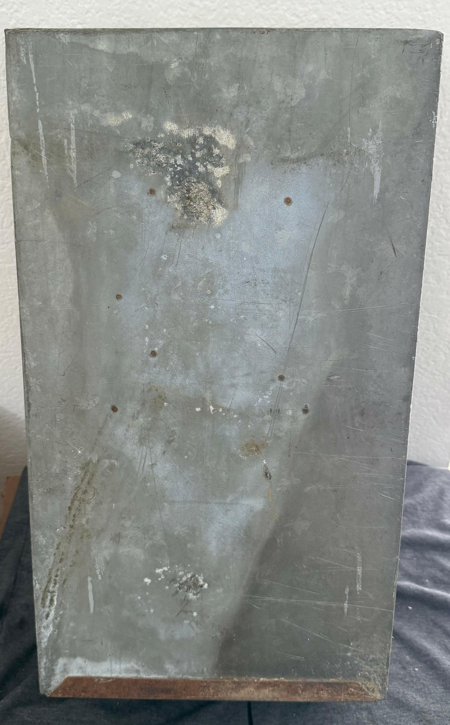 Rectangular metal block with visible wear and tear on a plain background