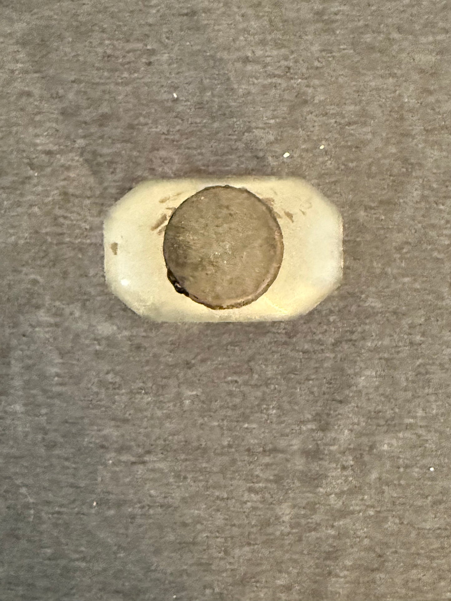 Small cylindrical object with a metallic cap on a textured gray background